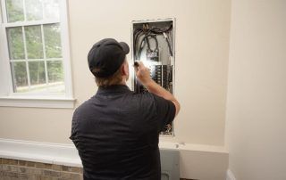 A man is working on an electrical box in a room.