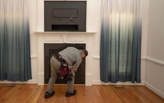 A man is kneeling down in front of a fireplace in a living room.