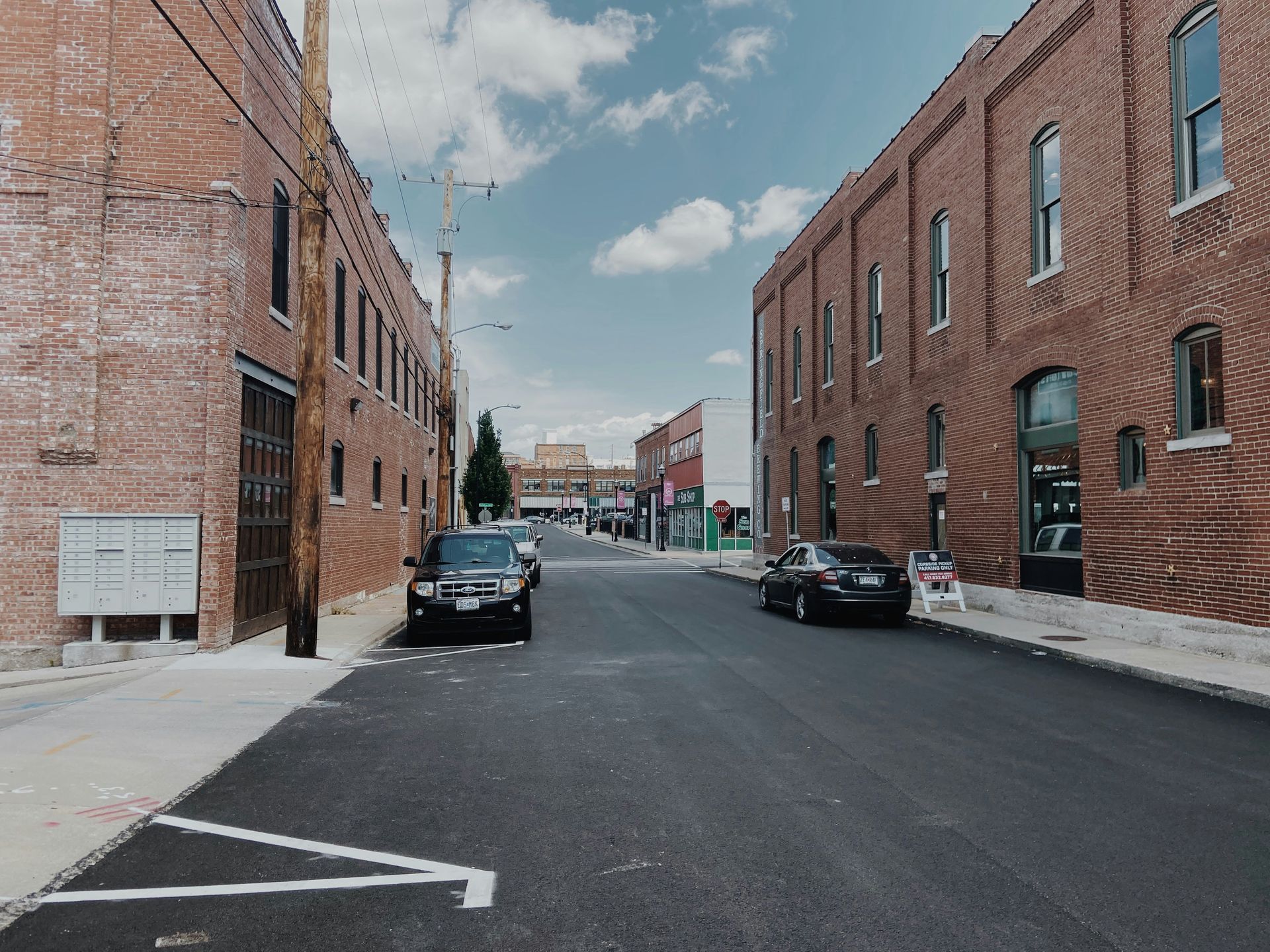 A car is parked on the side of the road in front of a brick building.