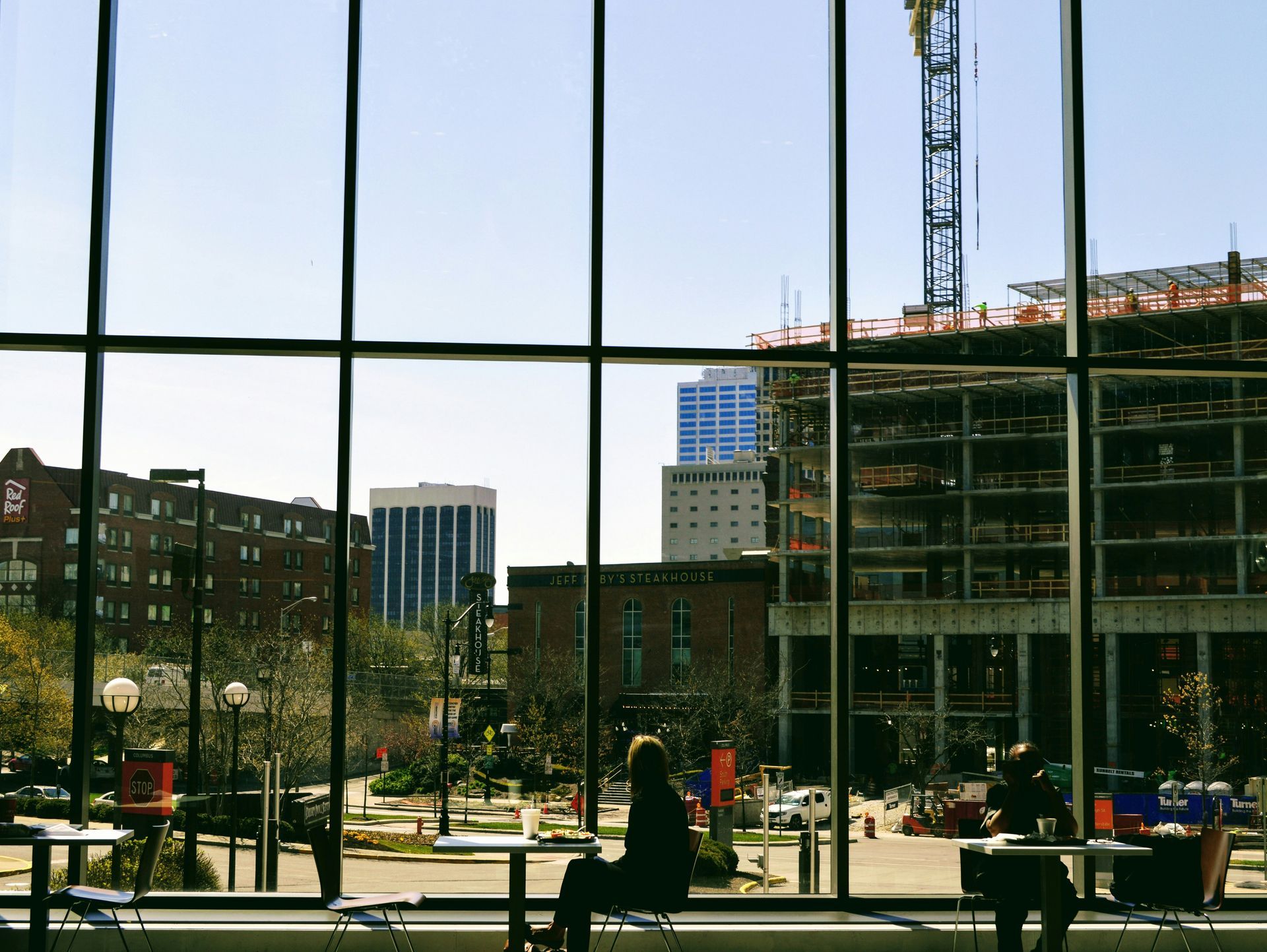 A woman sits in front of a large window looking out to a city