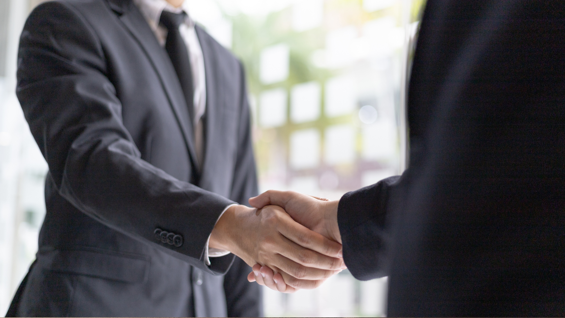 A man in a suit and tie is shaking hands with another man.