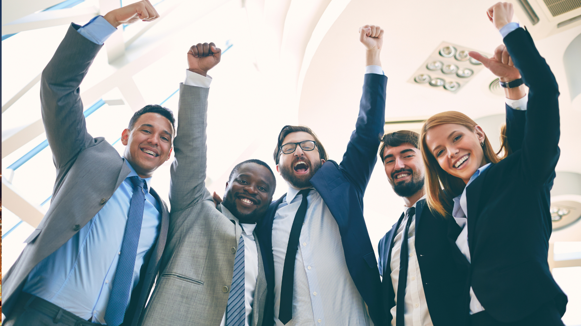 A group of business people are standing next to each other with their arms in the air.