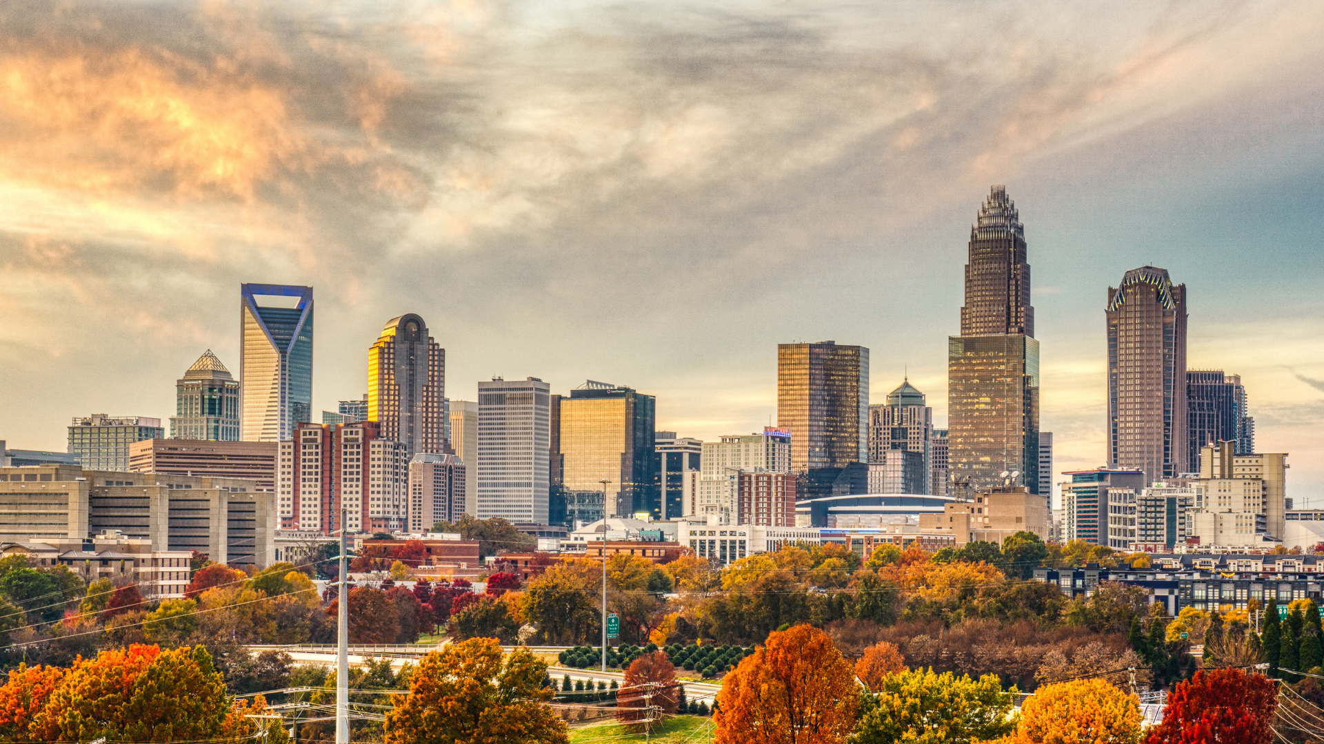 Charlotte, North Carolina skyline with skyscrapers, during autumn, with colorful trees and cloudy sky.