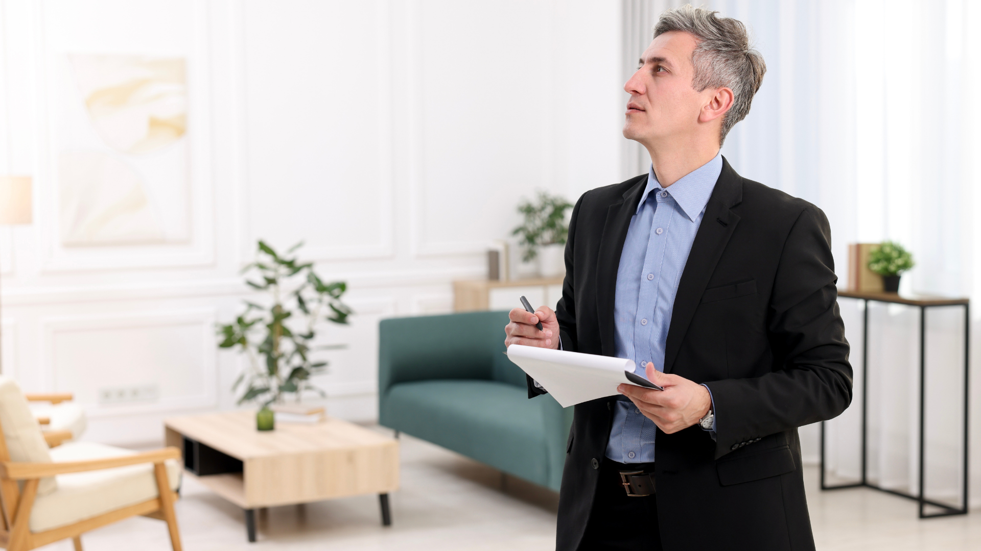 Real estate agent inspecting a room, looking up, holding a notepad and pen.