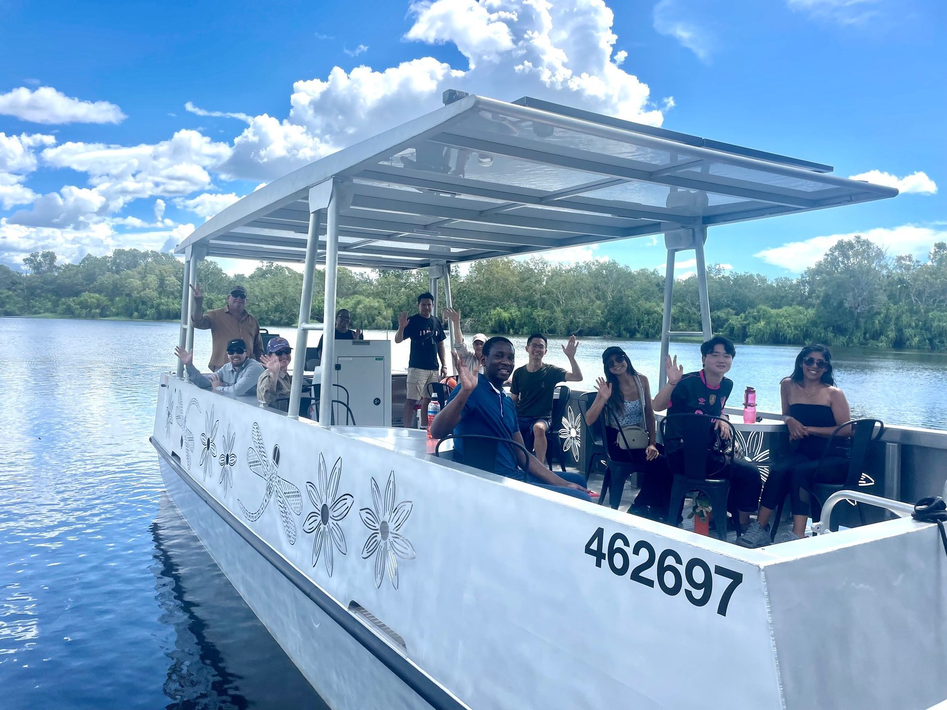 White pontoon boat with passengers on a lake under a cloudy sky — Kakadu Billabong Safari Camp in Kakadu, NT