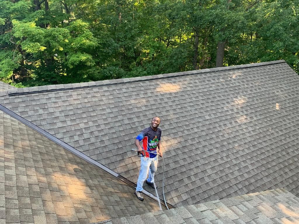 A man is standing on top of a roof with a ladder.