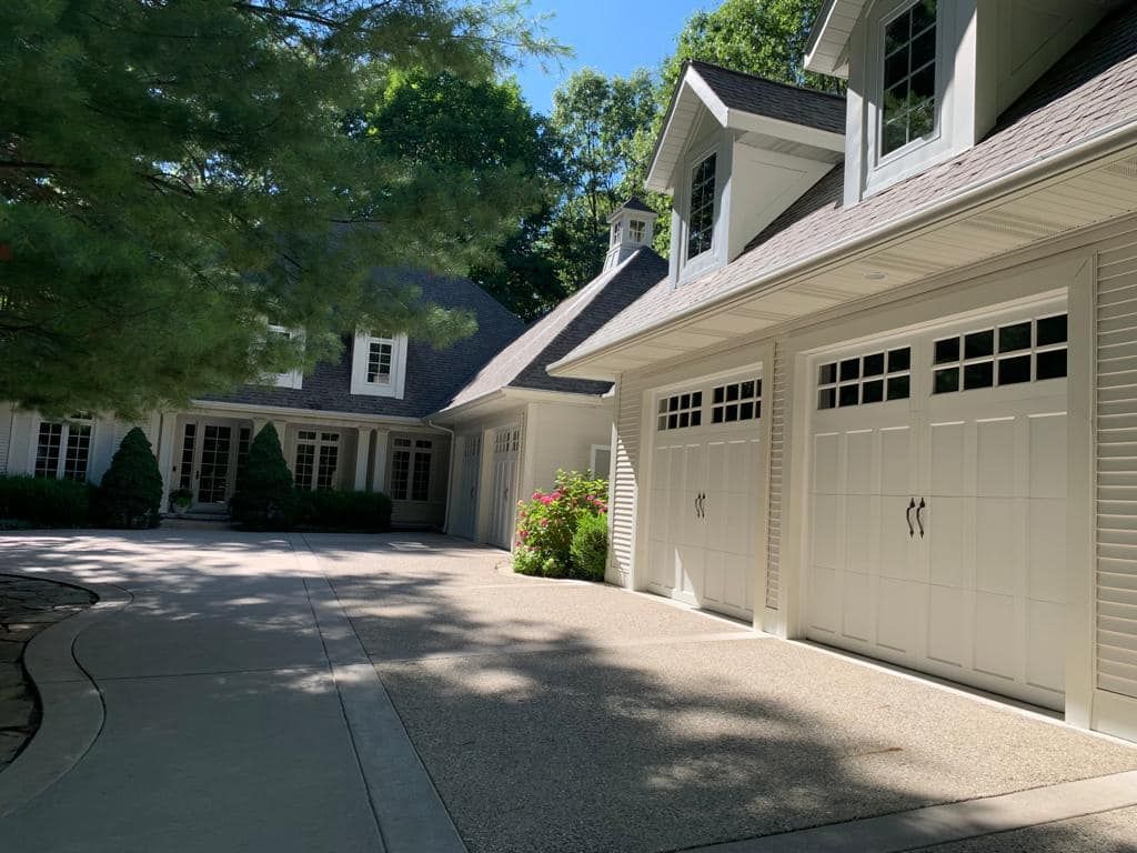 A large white house with three garage doors and a driveway.