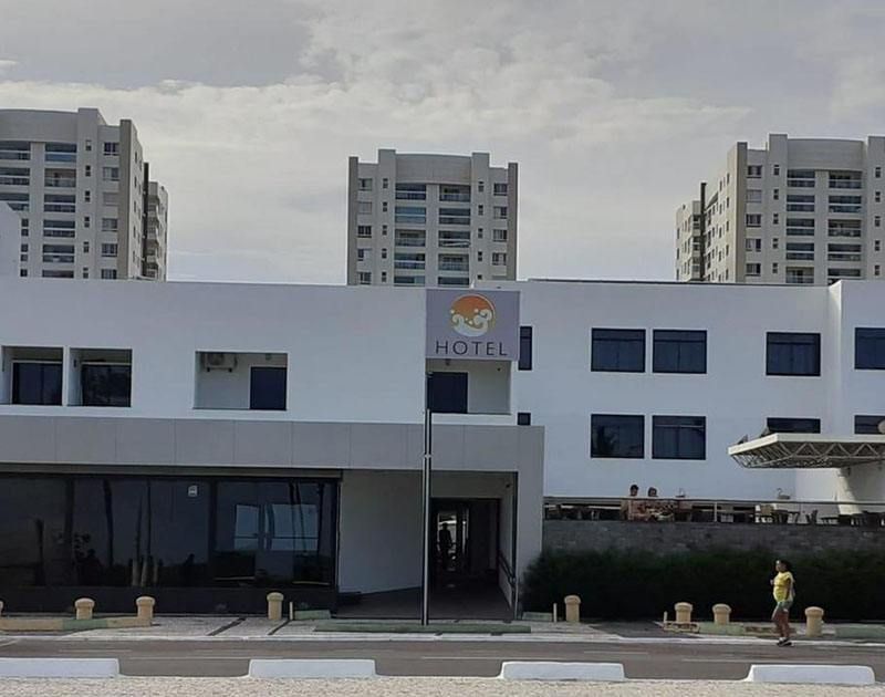 Fachada branca de hotel com a placa 