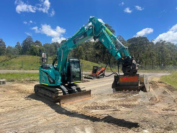 Green excavator on a dirt road, preparing a construction site on a sunny day.