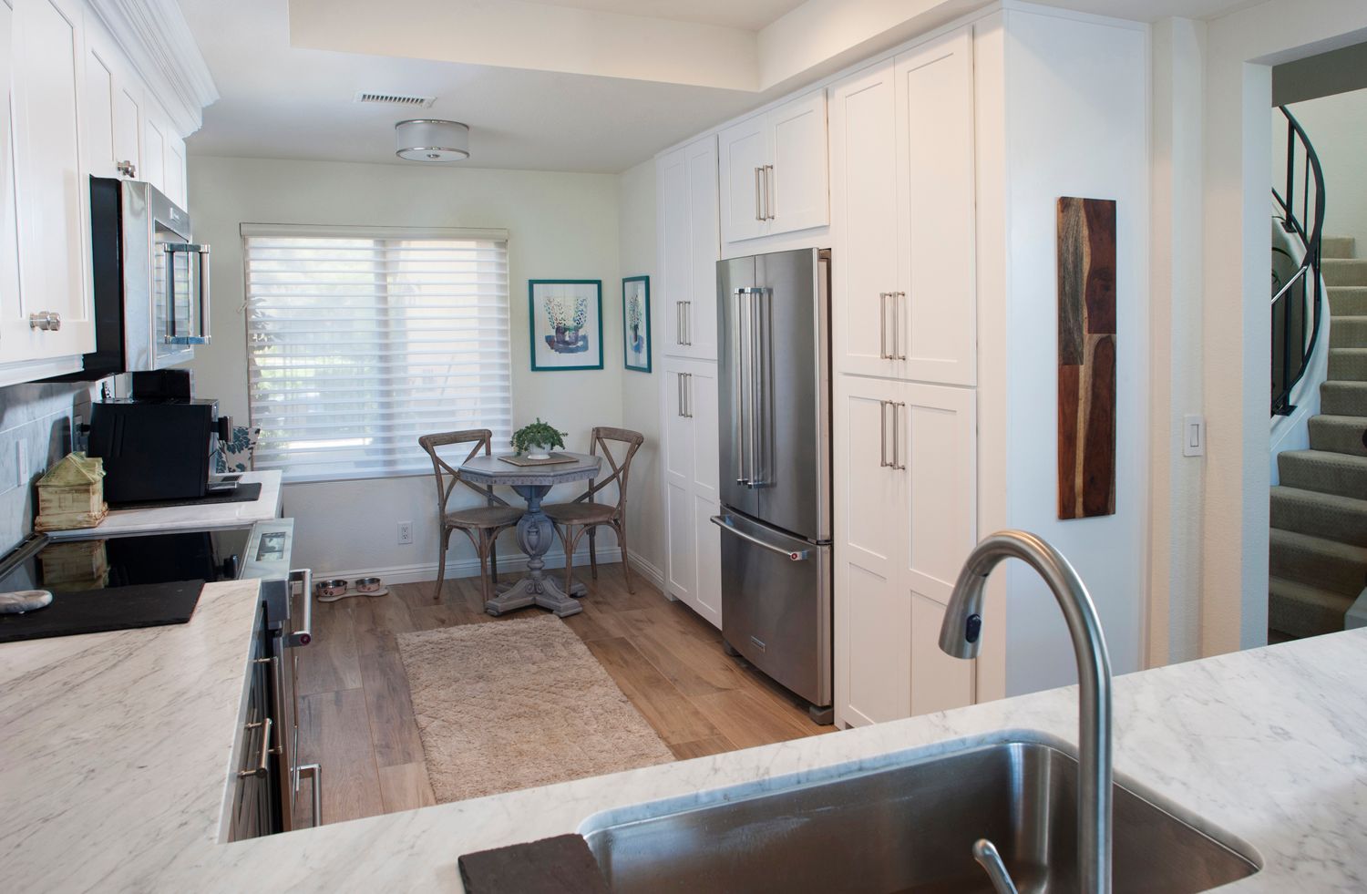 White kitchen with stainless steel refrigerator and small dining table.