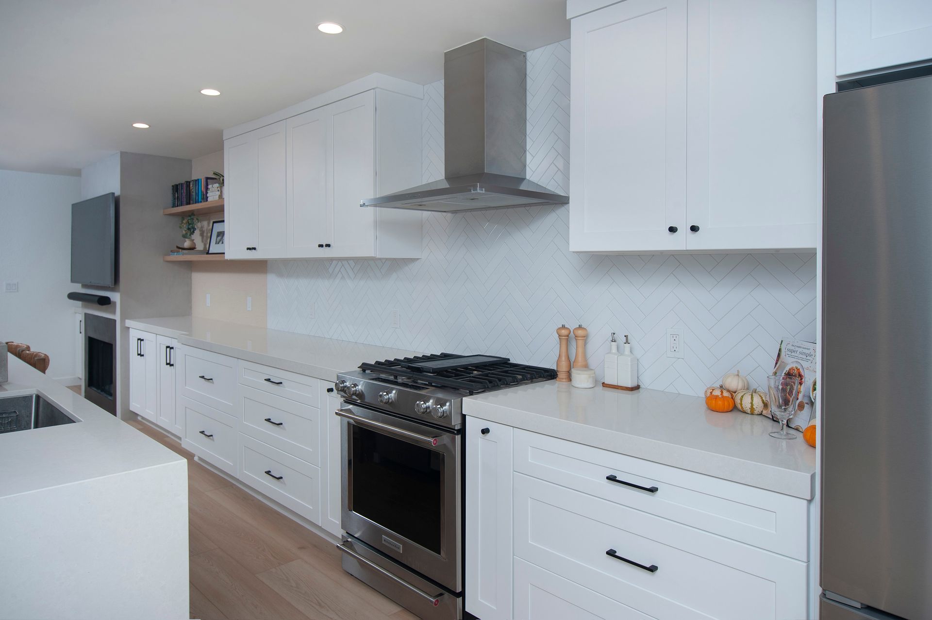 Modern white kitchen with stainless steel appliances, white countertops, and gas range.