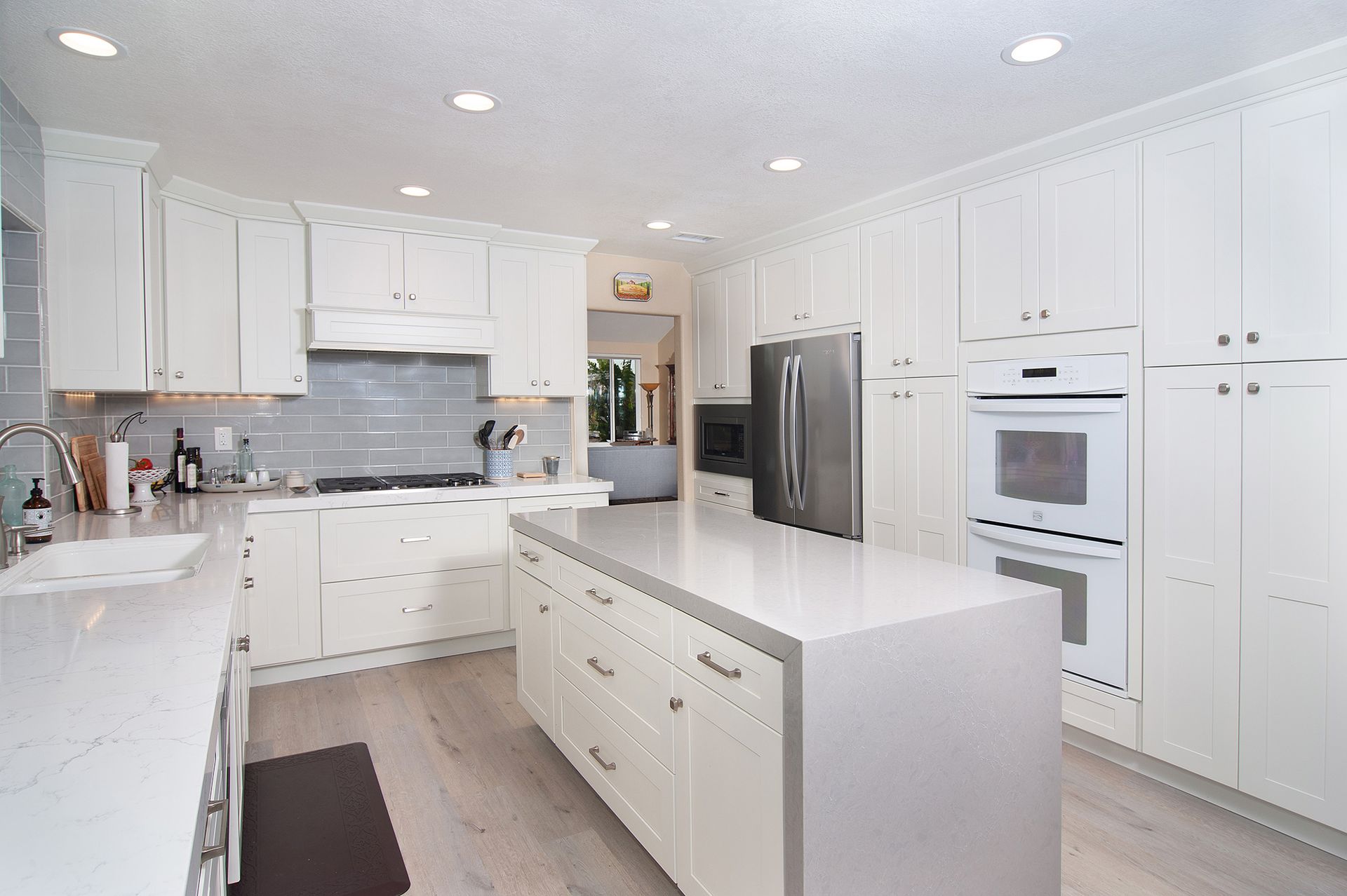 White kitchen with island, cabinets, appliances, and light wood floors.