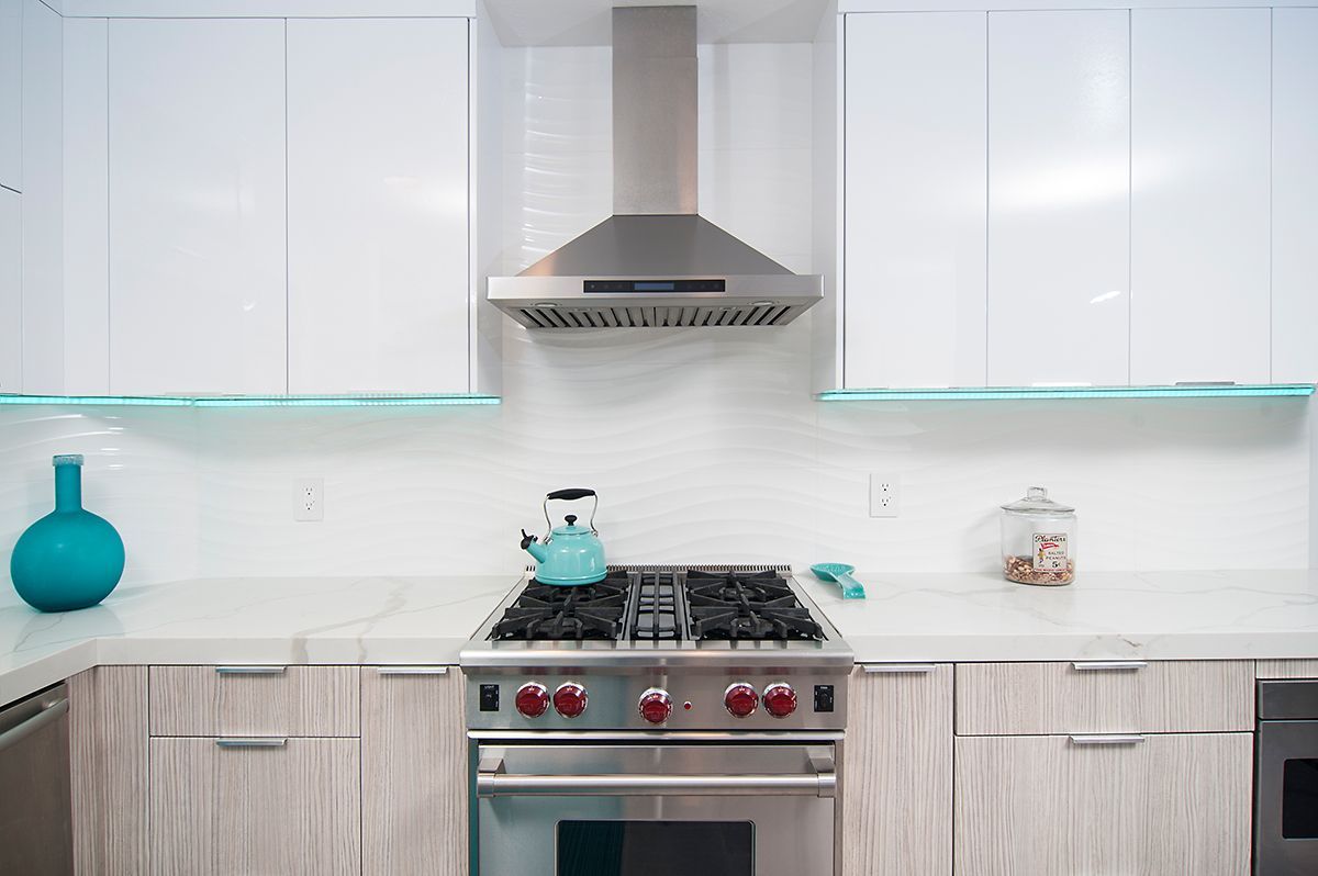 Modern kitchen with white and wood cabinets, stainless steel appliances, and turquoise decor.