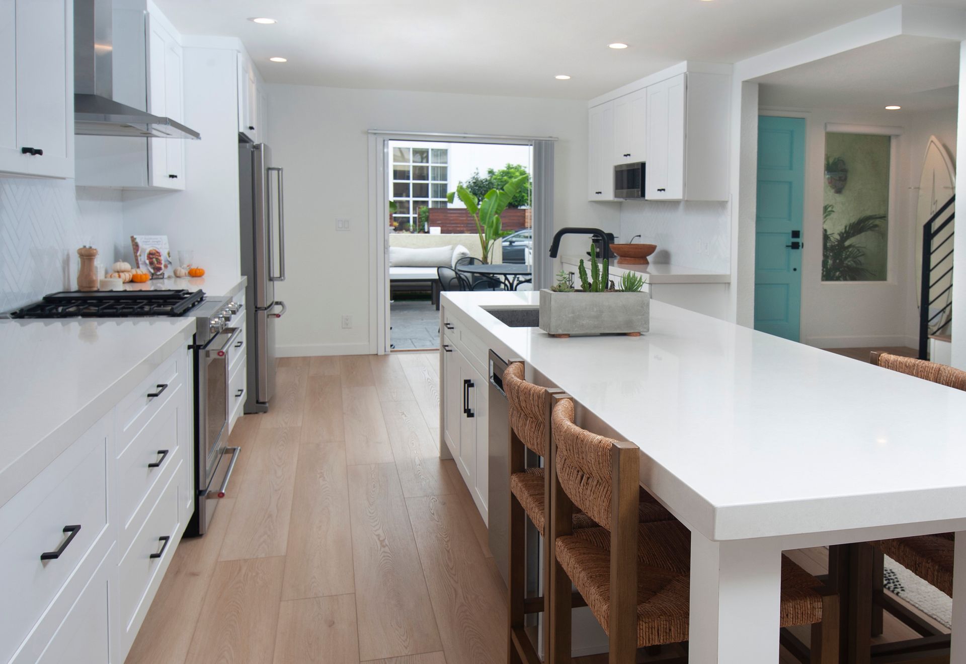 Bright white kitchen with island, stainless steel appliances, and wooden floors.