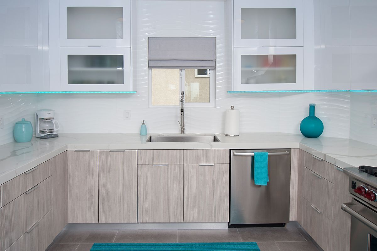 Modern kitchen with light wood cabinets, stainless steel appliances, and turquoise accents.