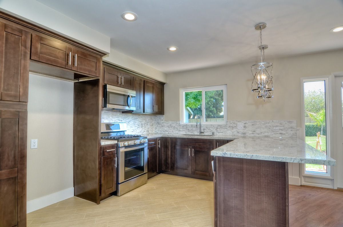 Dark wood kitchen with stainless steel appliances, island, and a window.