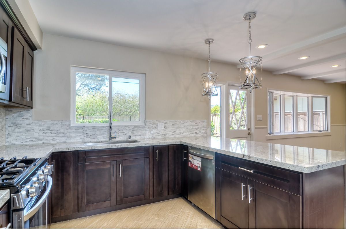 Kitchen with dark brown cabinets, white countertops, and a stainless steel dishwasher.