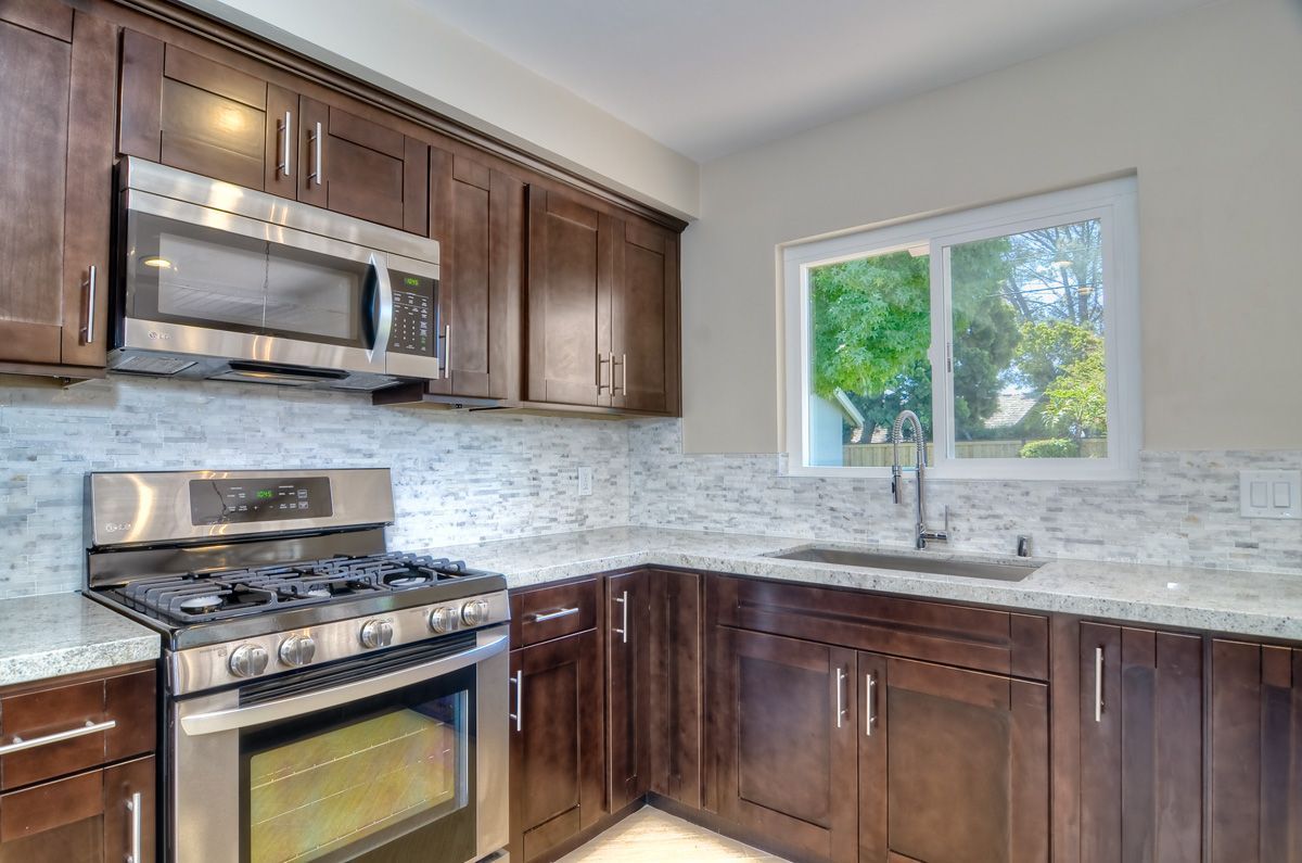 Brown kitchen cabinets and appliances, with a window and sink area.