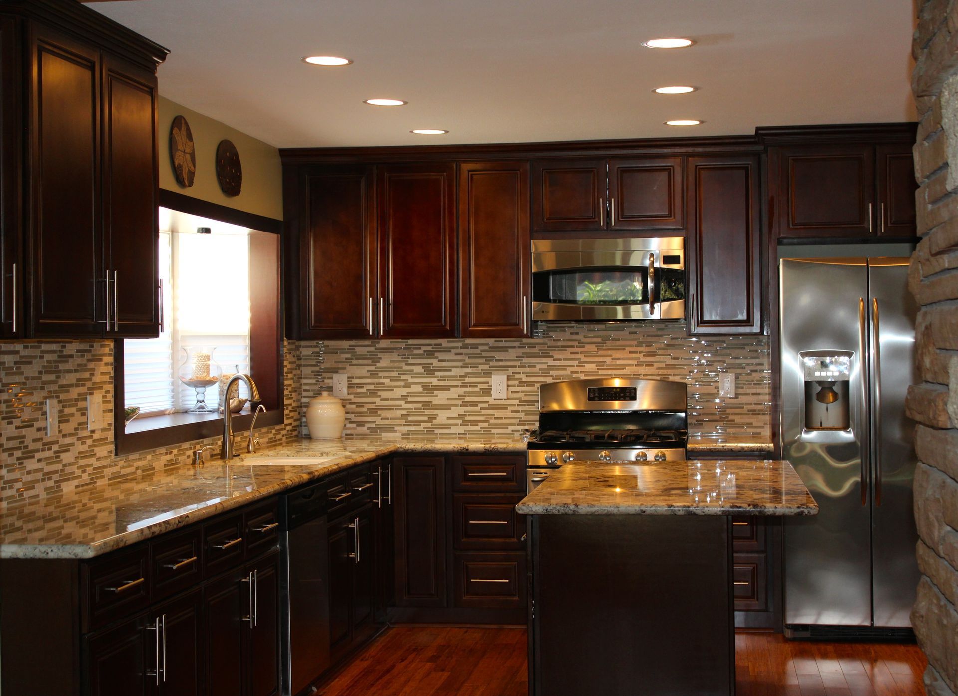 Dark wood kitchen with stainless steel appliances and stone accent wall.