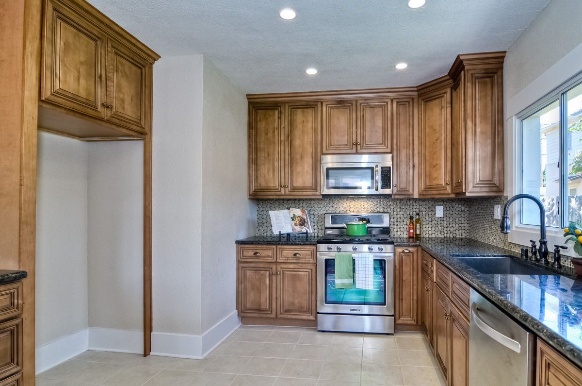 Kitchen with wood cabinets, stainless steel appliances, dark countertops, and a window.