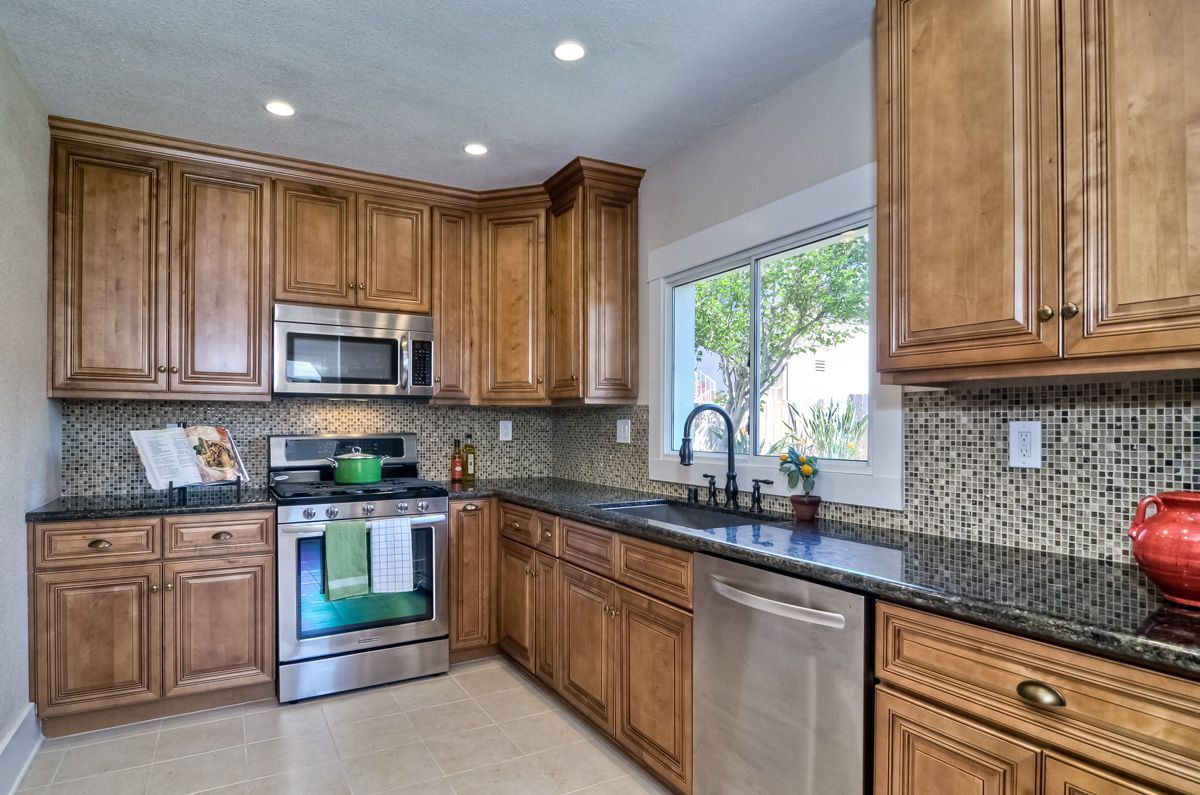 Kitchen with light brown cabinets, stainless steel appliances, and dark countertops.