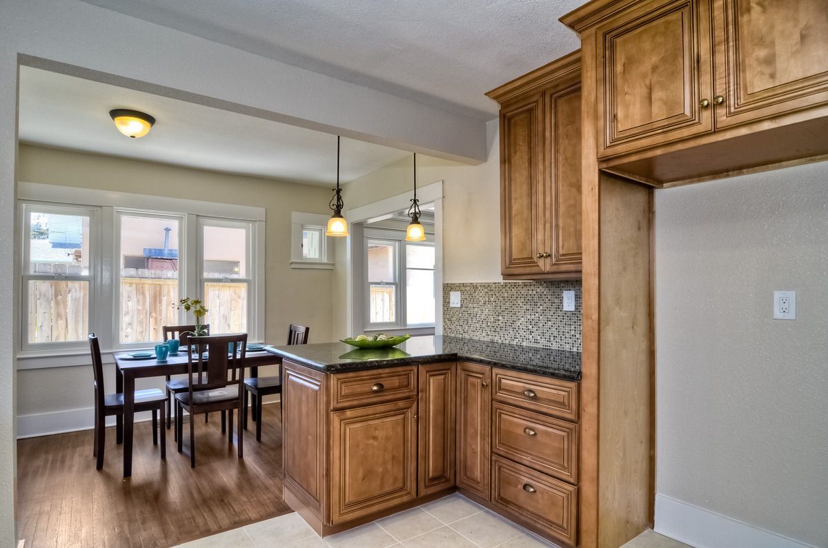 Kitchen with wooden cabinets, island, and a dining area with a table and chairs.