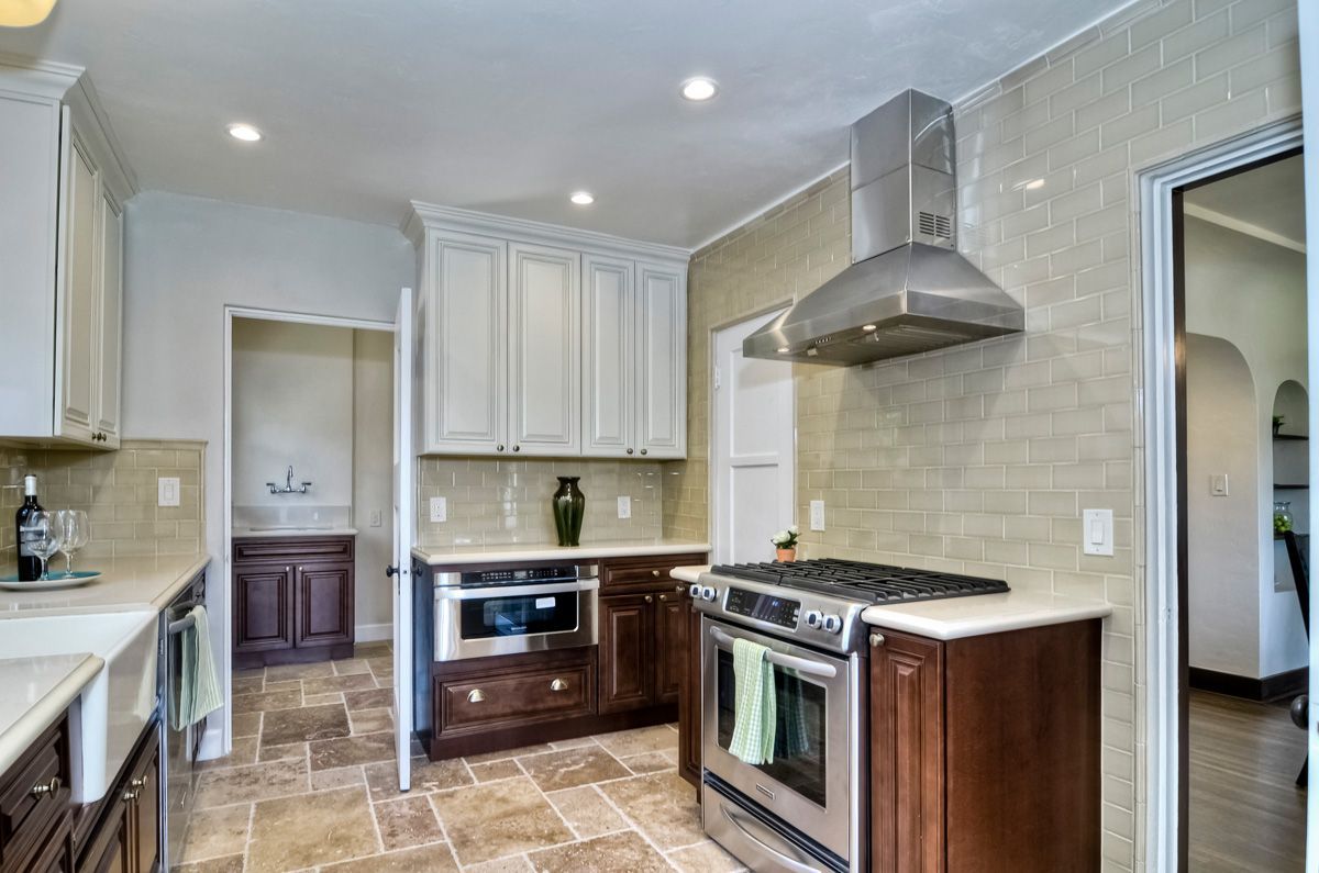 Kitchen with two-tone cabinets, stainless steel appliances, and tiled backsplash. Brown and beige tones.
