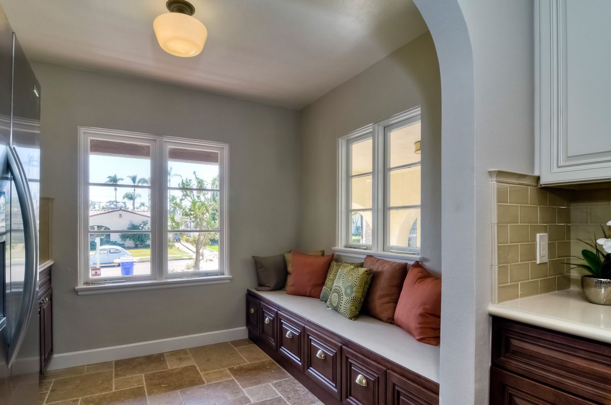 Cozy window seat with pillows in a room with a view, cabinets below, and warm colors.