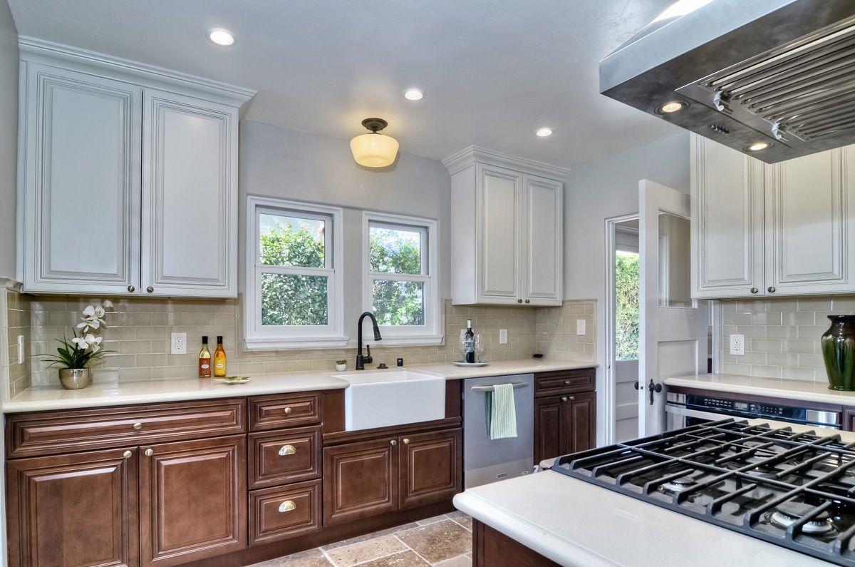 Kitchen with white upper cabinets, brown lower cabinets, stainless steel appliances, and windows.