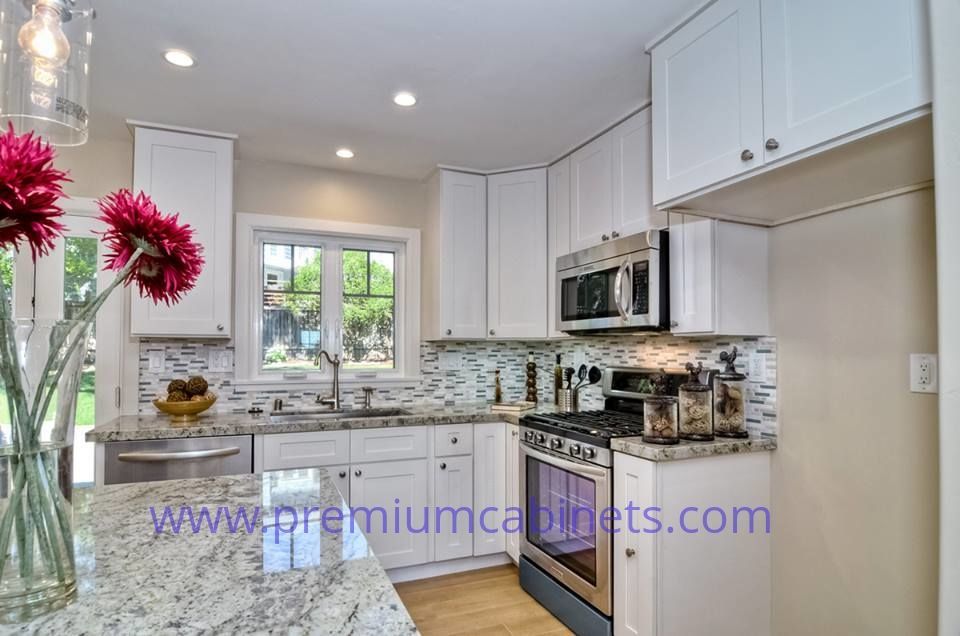 White kitchen with granite countertops, stainless steel appliances, and a window.
