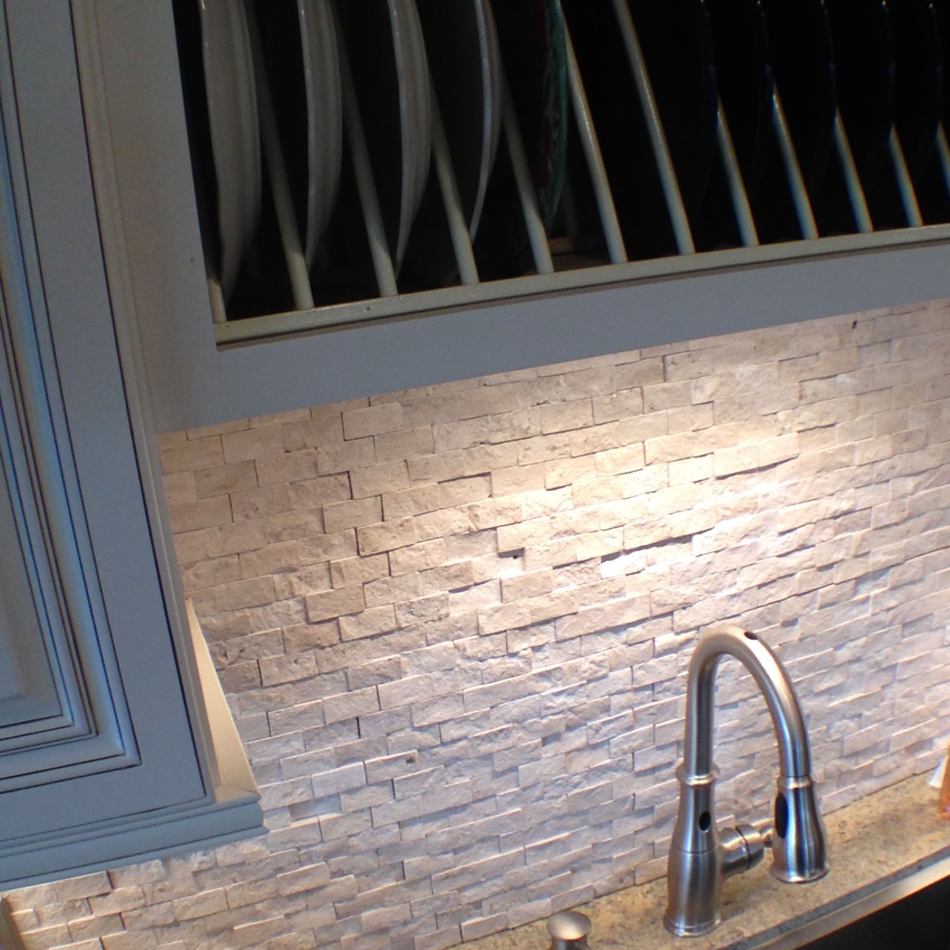 Kitchen sink with brushed nickel faucet against a stacked stone backsplash.