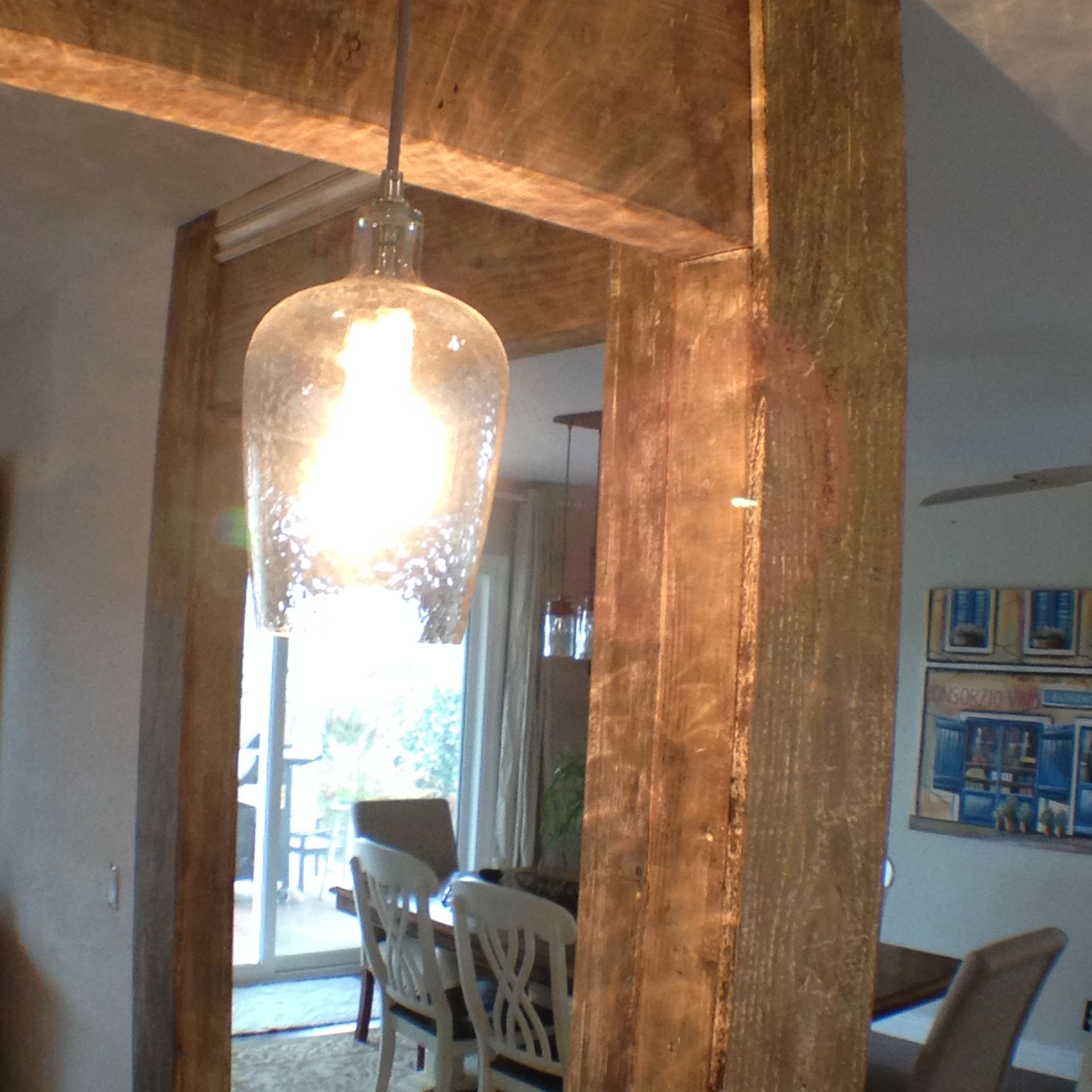Wooden entryway with hanging light fixture illuminates dining area.