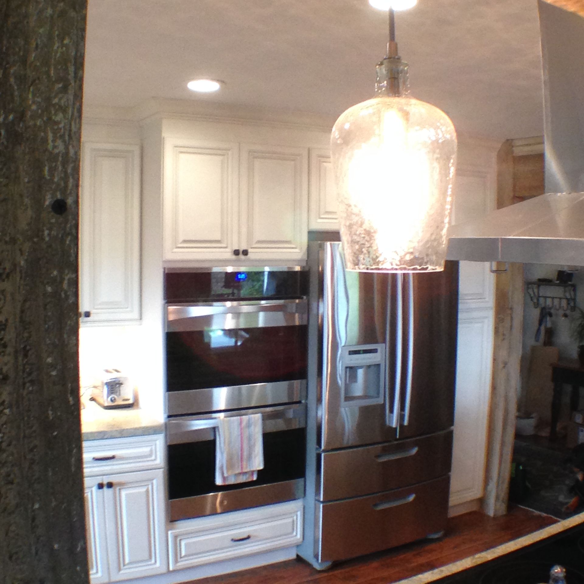 Kitchen with white cabinets, stainless steel appliances, and a hanging glass light fixture.