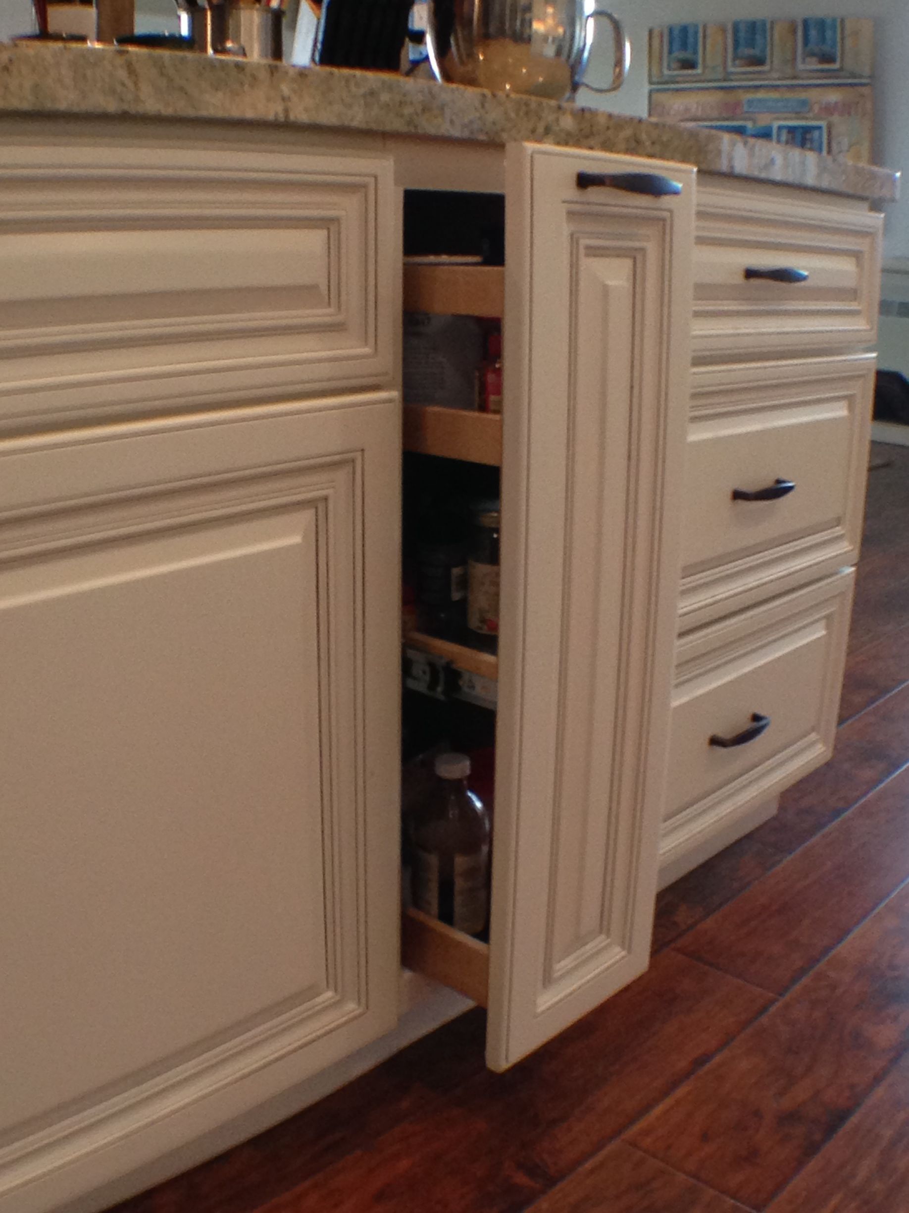 White kitchen cabinet with pull-out spice rack open, revealing spice bottles.