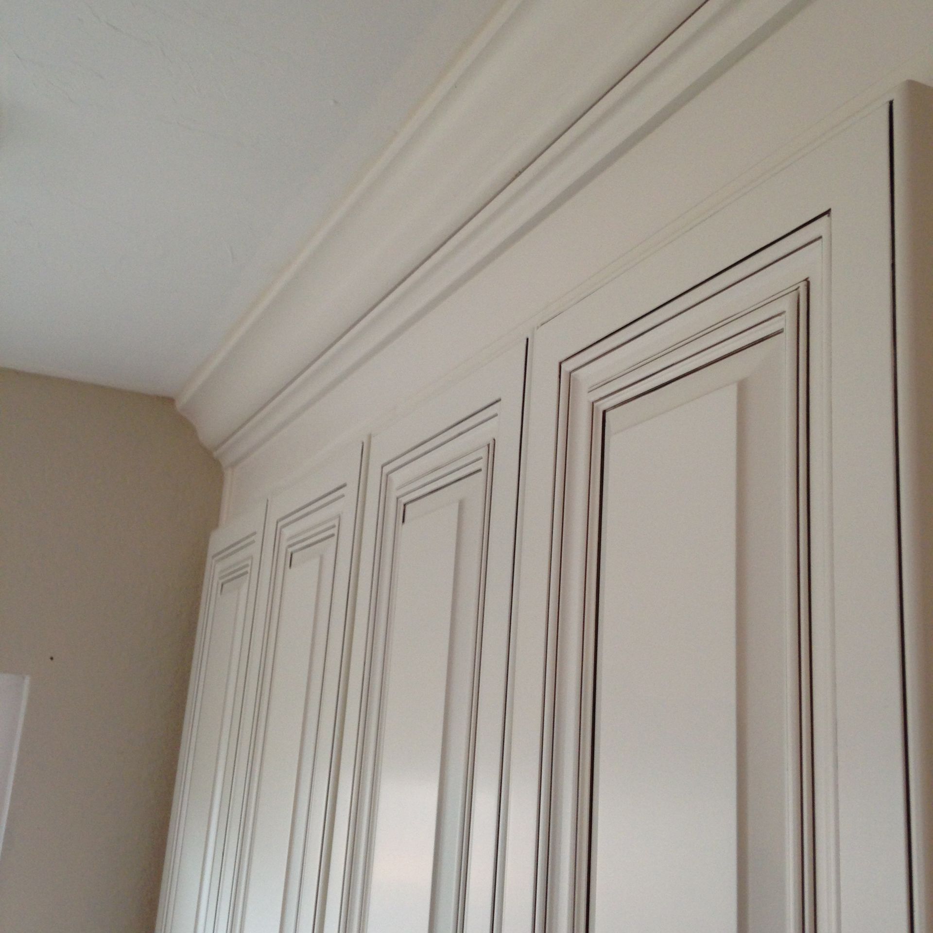 White cabinets with crown molding and a light-colored wall and ceiling.