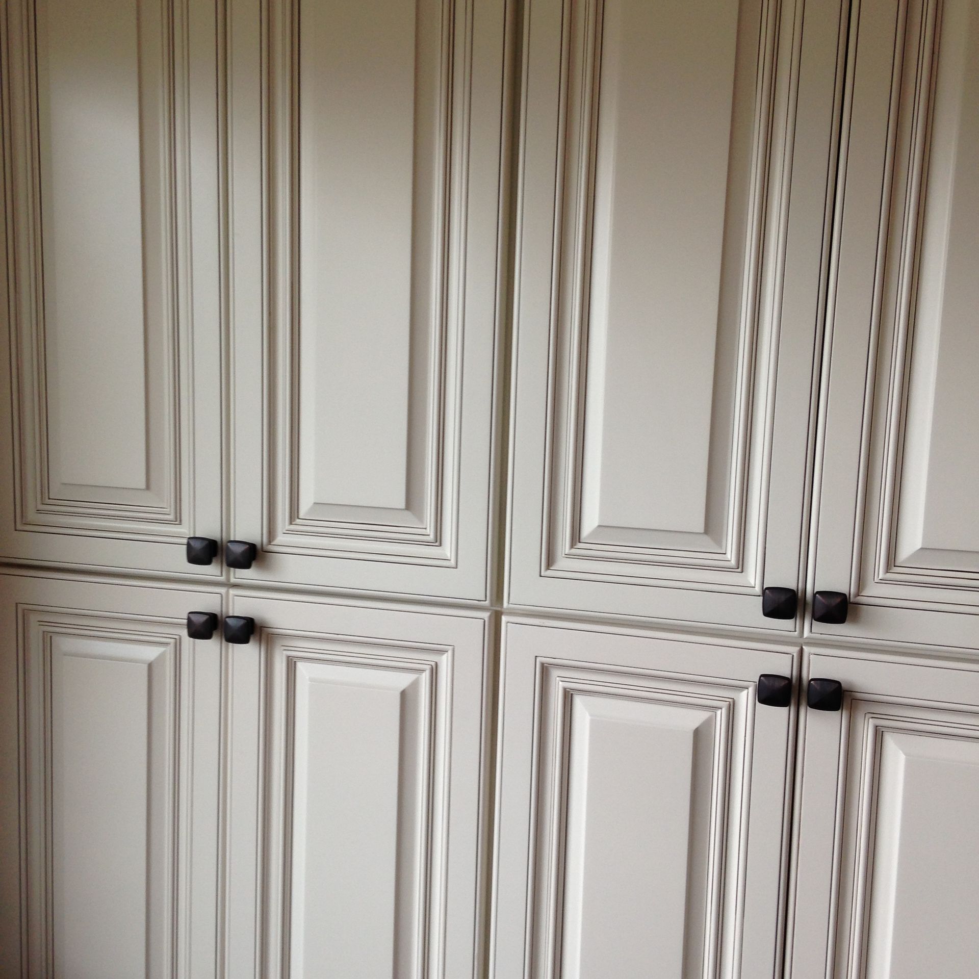 Cream-colored cabinets with black knobs.