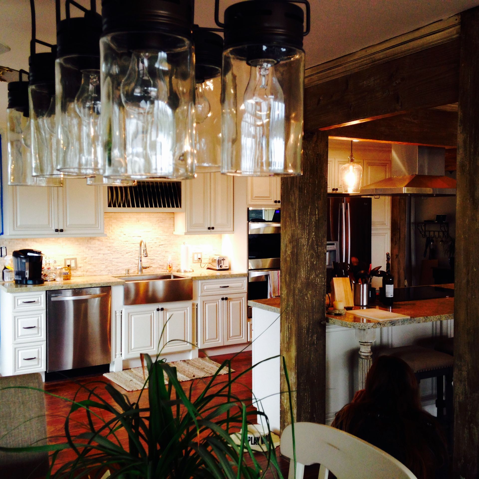 Kitchen with white cabinets, stainless steel appliances, and mason jar light fixtures.