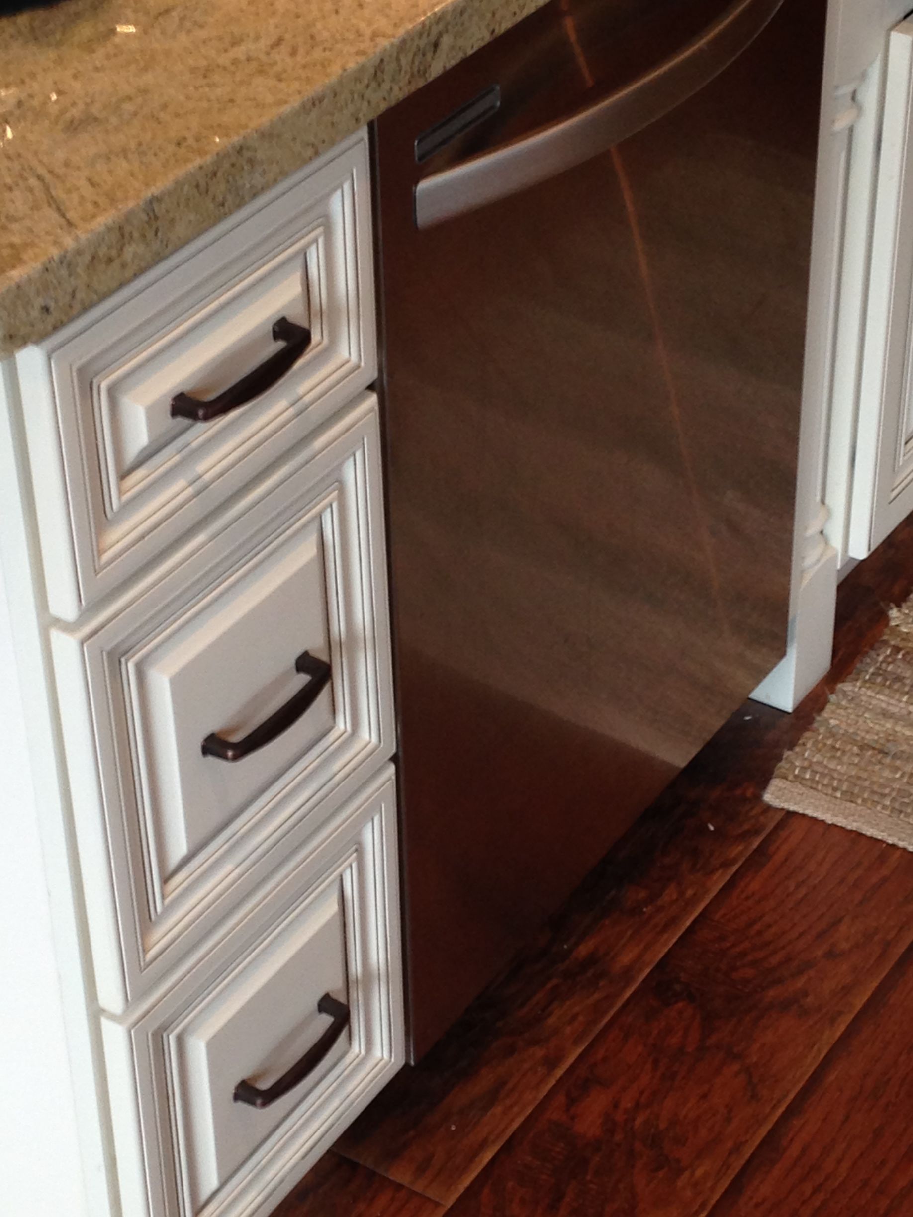 Kitchen cabinet with drawers next to a stainless steel dishwasher.