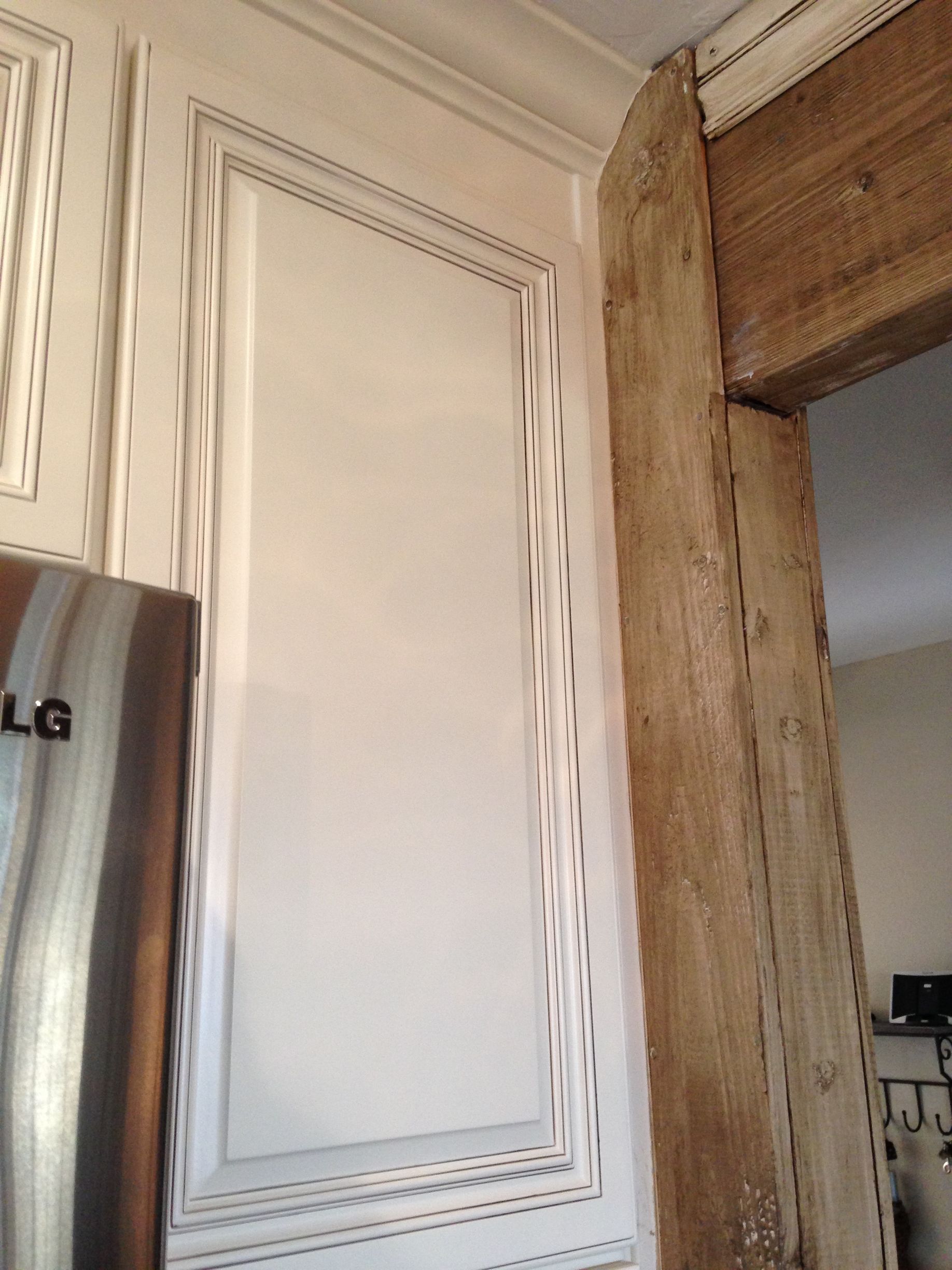 White kitchen cabinet next to a wooden doorway.