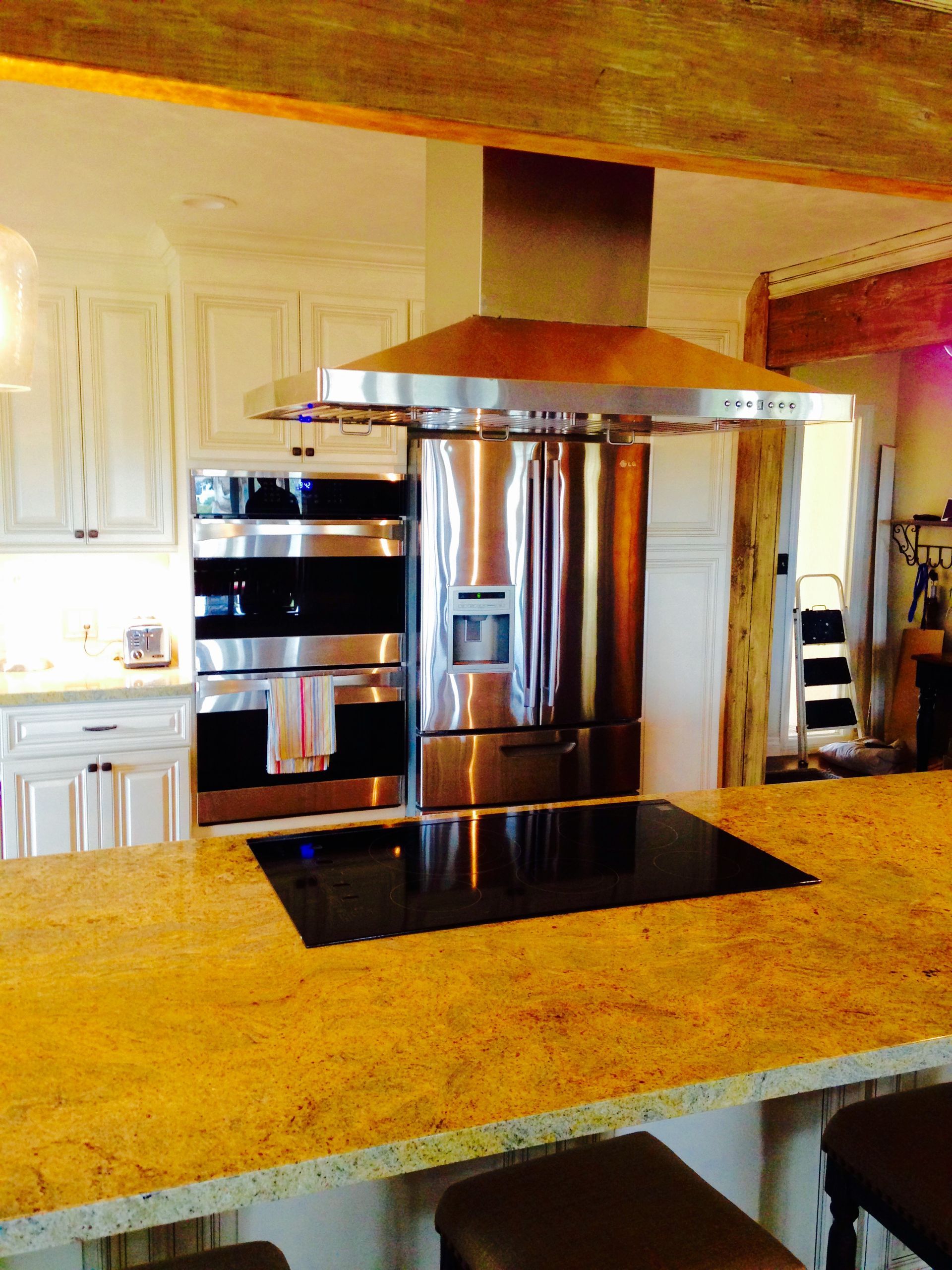 Kitchen with stainless steel appliances: oven, refrigerator, range hood. Granite countertops, white cabinets.
