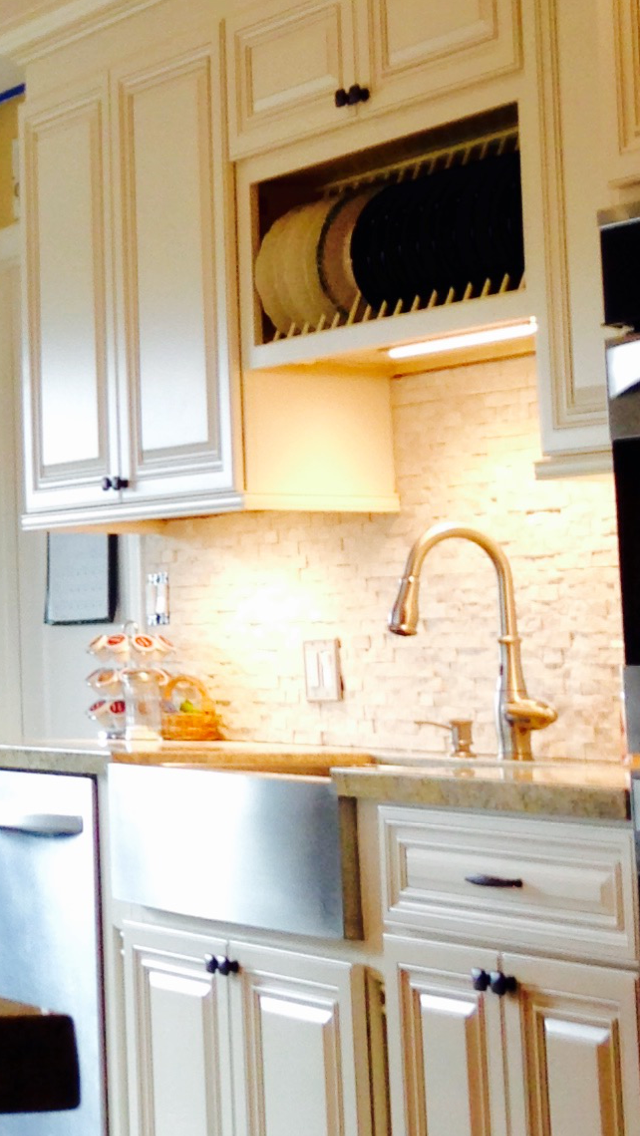 Cream-colored kitchen cabinets with a stainless steel sink and a built-in plate rack.