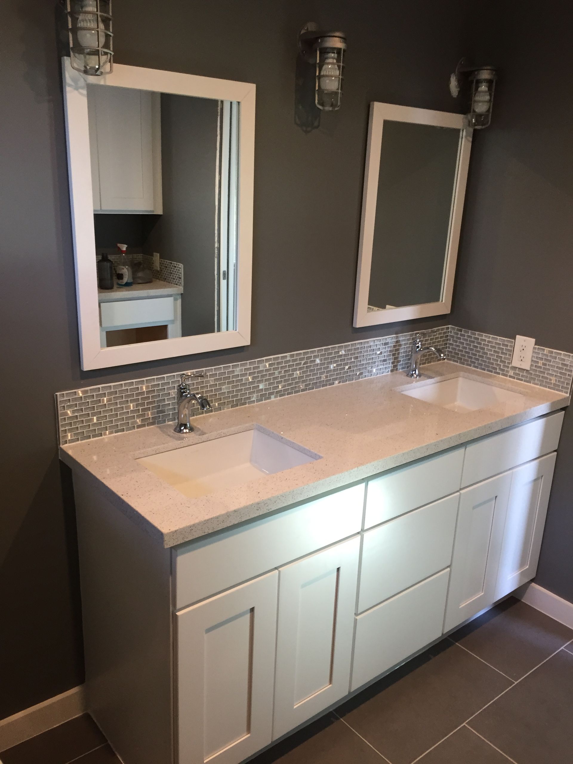Gray and white bathroom vanity with two mirrors, sinks, and lights.