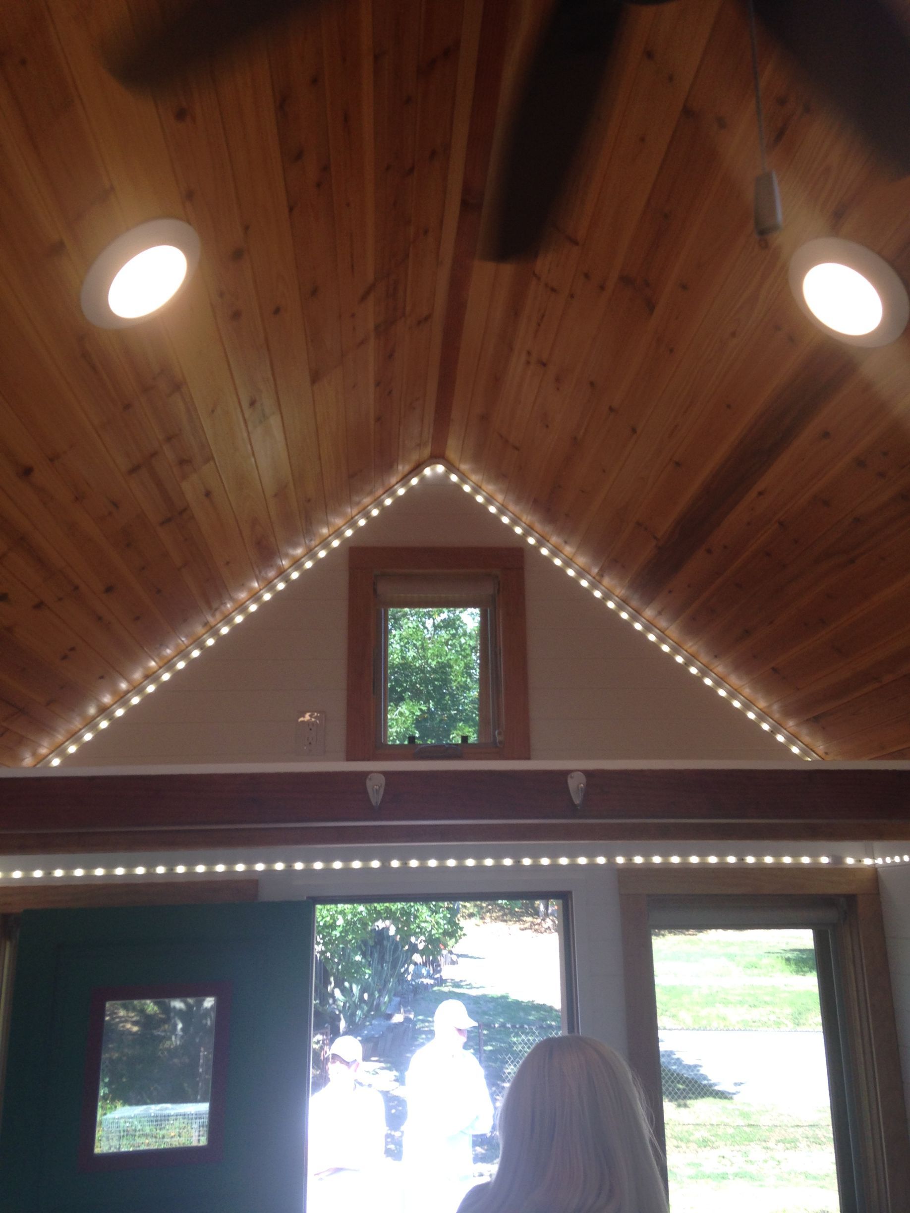 Wooden ceiling with recessed lights and string lights, above a doorway and window.