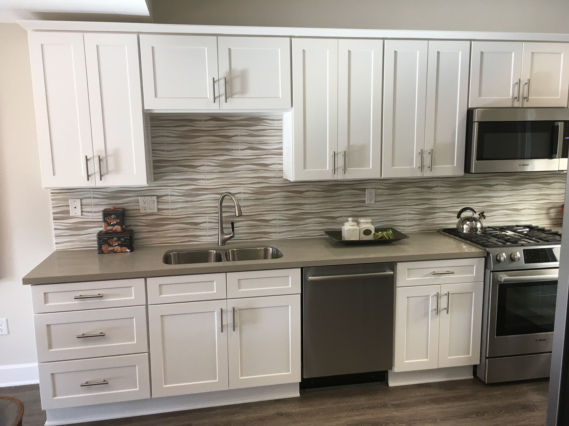 White kitchen cabinets, stainless steel appliances, and a neutral-toned backsplash.
