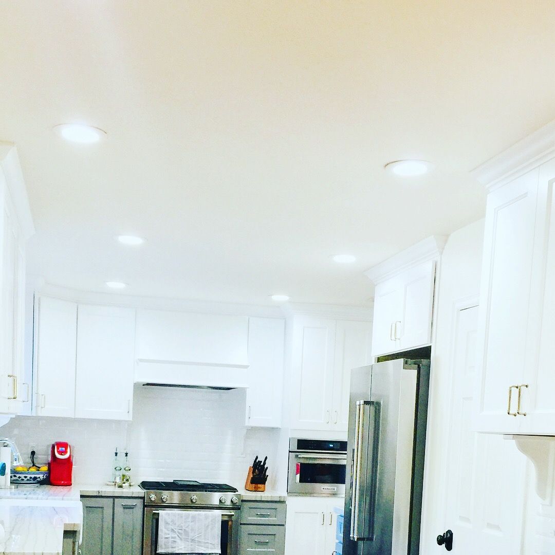 White kitchen with gray accents, stainless steel appliances, and recessed lighting.