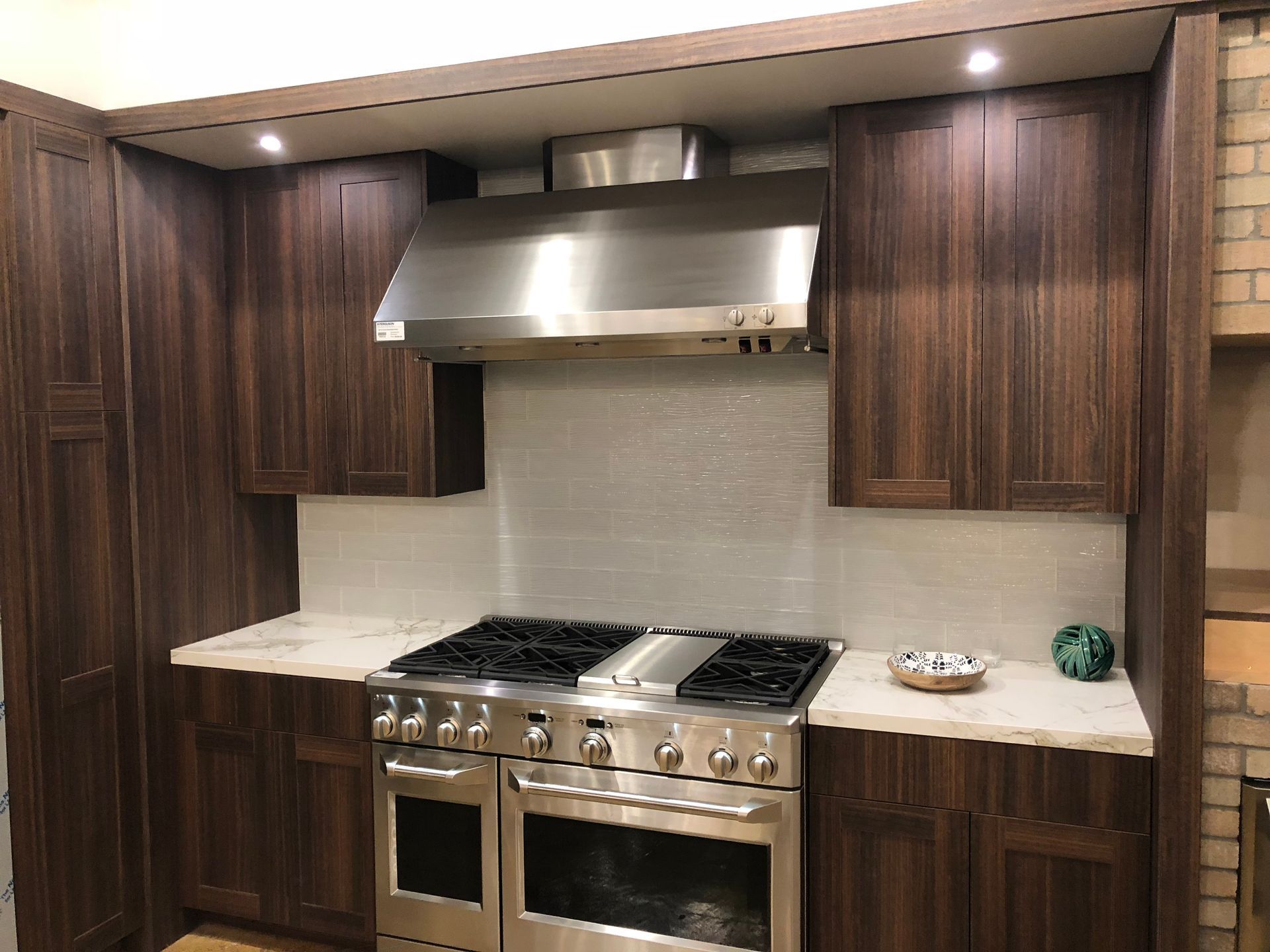 Dark wood kitchen cabinets surround a stainless steel range with a matching hood.