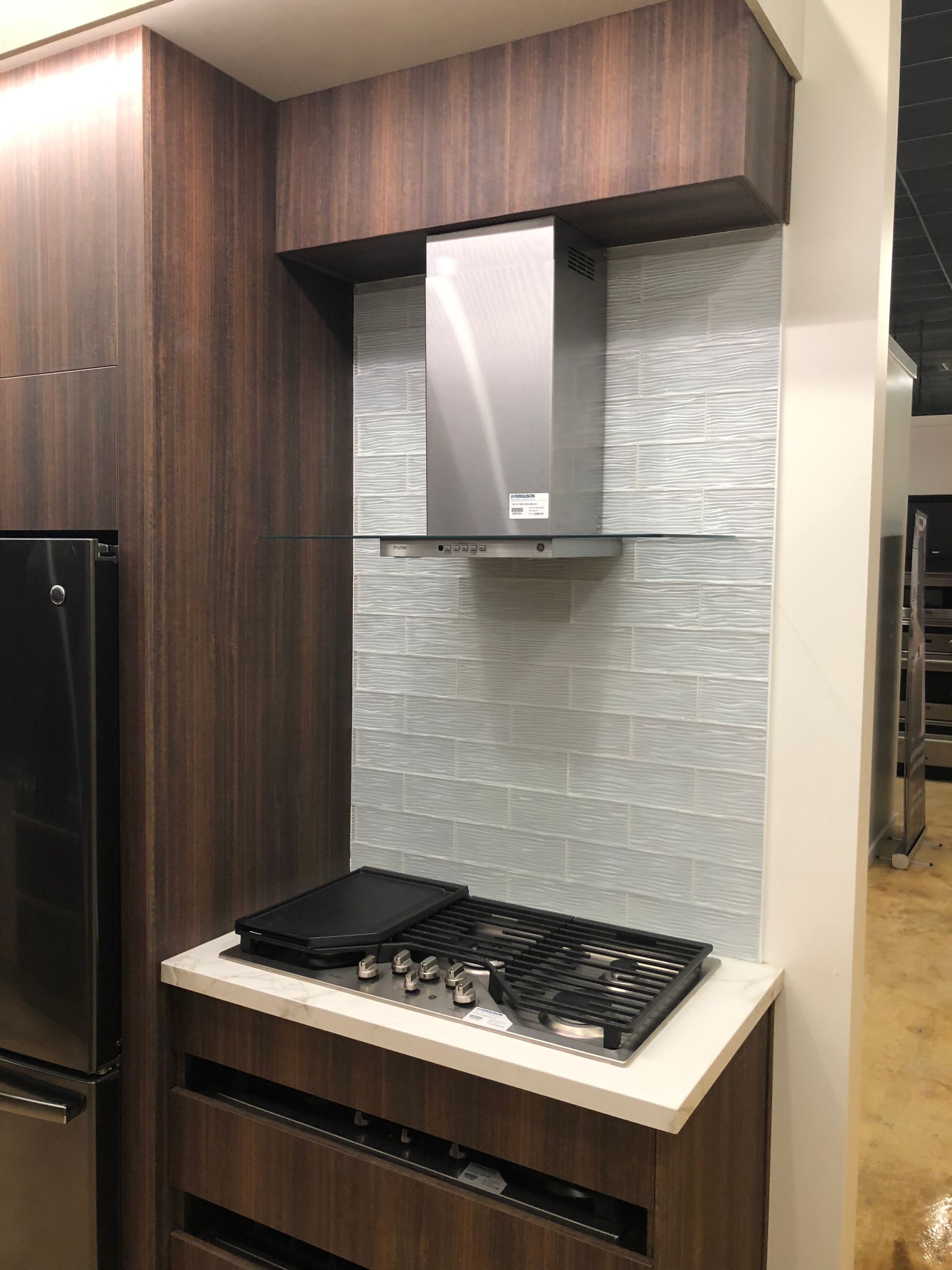 Kitchen area with gas cooktop, stainless steel hood, and dark wood cabinetry.
