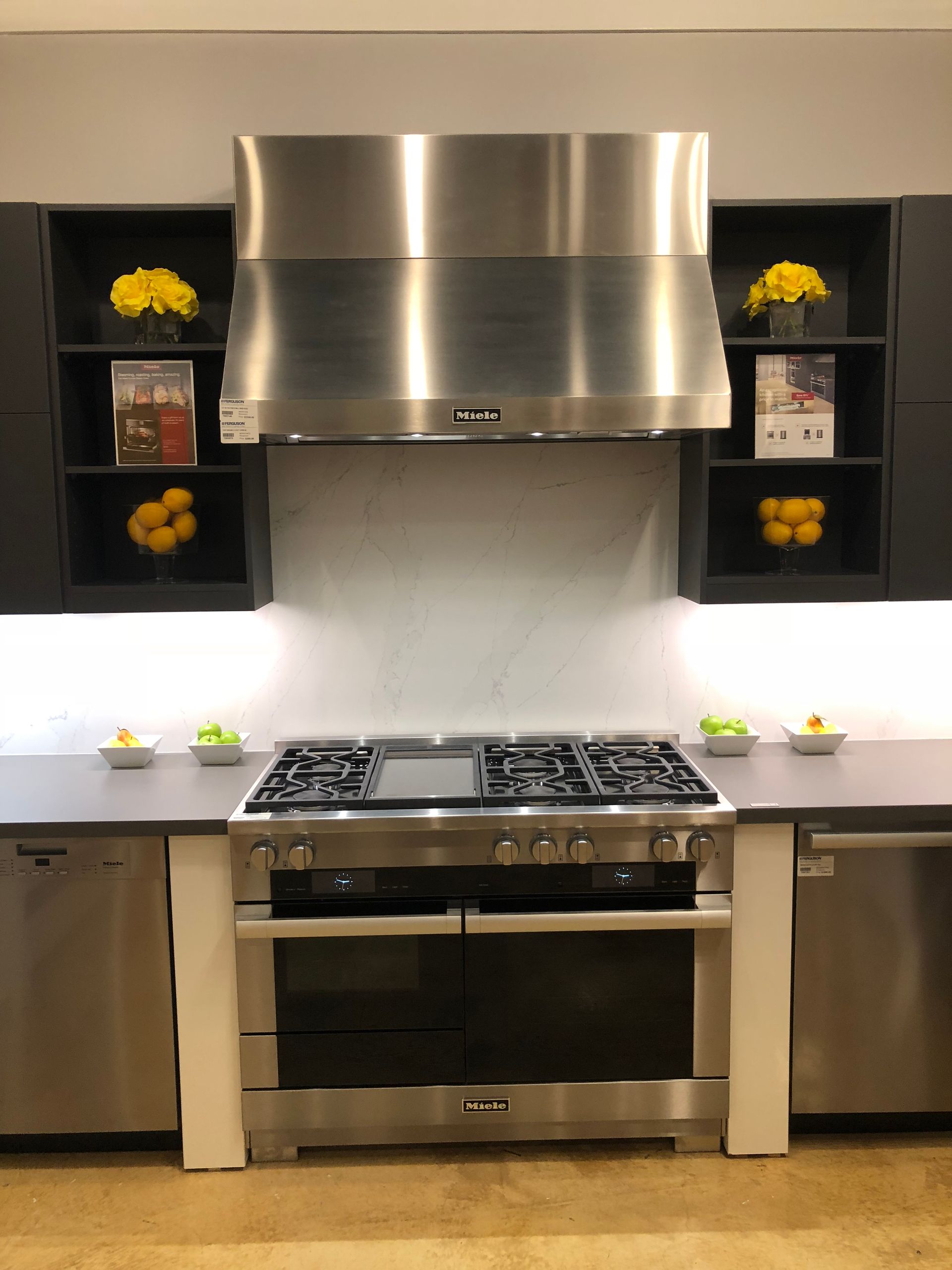 Kitchen with stainless steel range, hood, and dark cabinets, with yellow flowers and lemons as decor.
