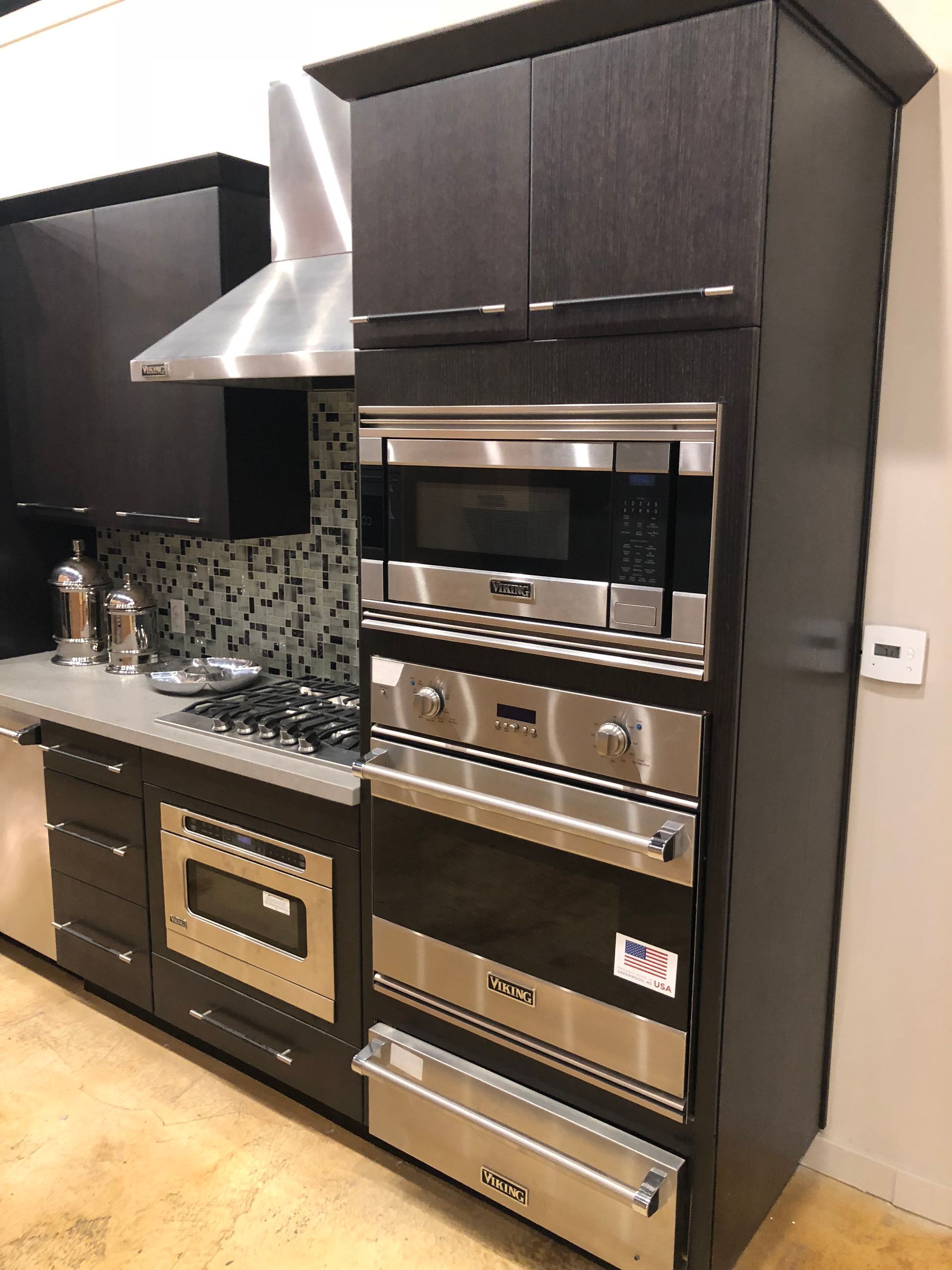 Dark wood kitchen with stainless steel appliances, including an oven, microwave, and range hood.