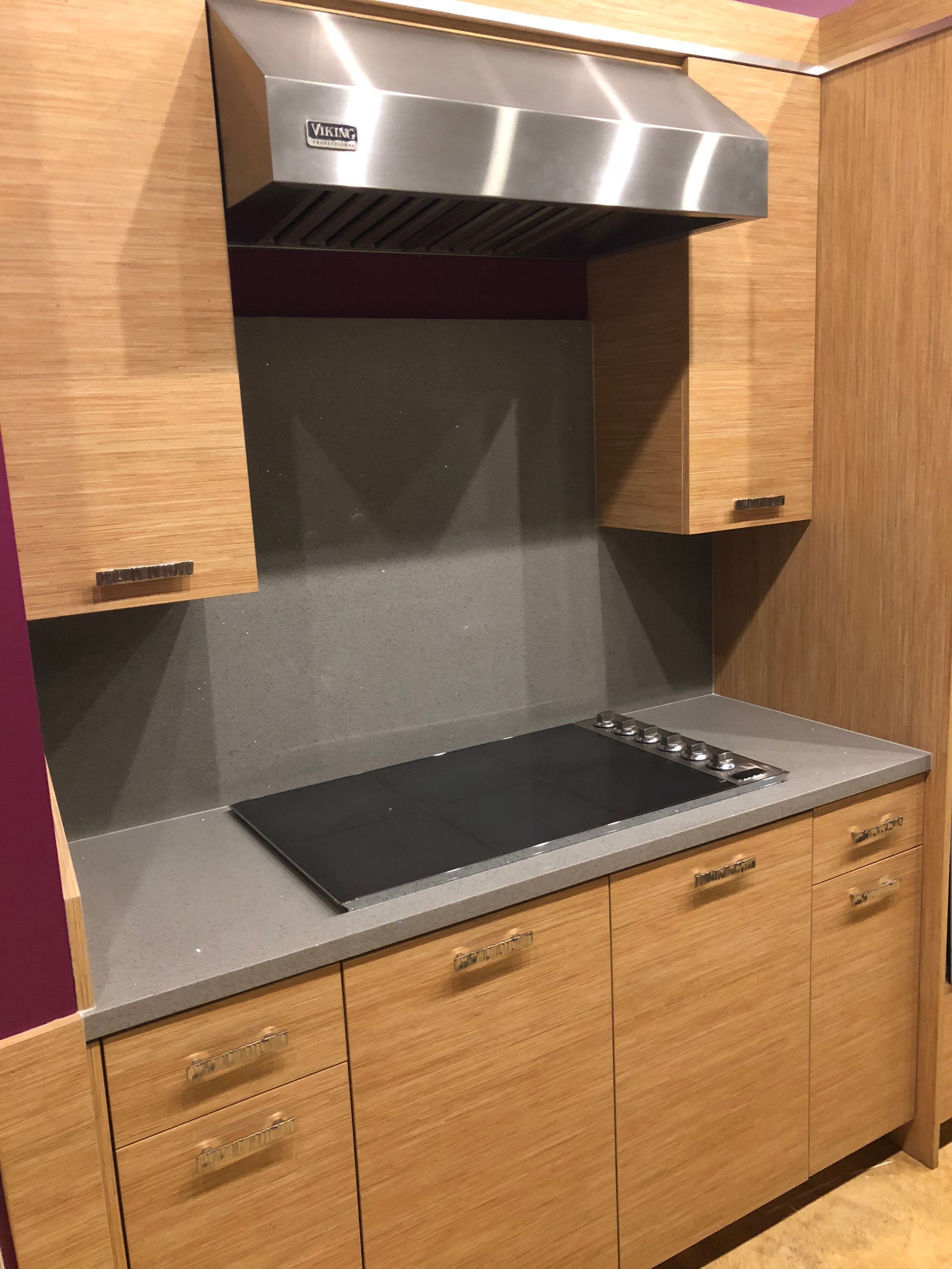 Kitchen with stainless steel range hood, wooden cabinets, and black cooktop.